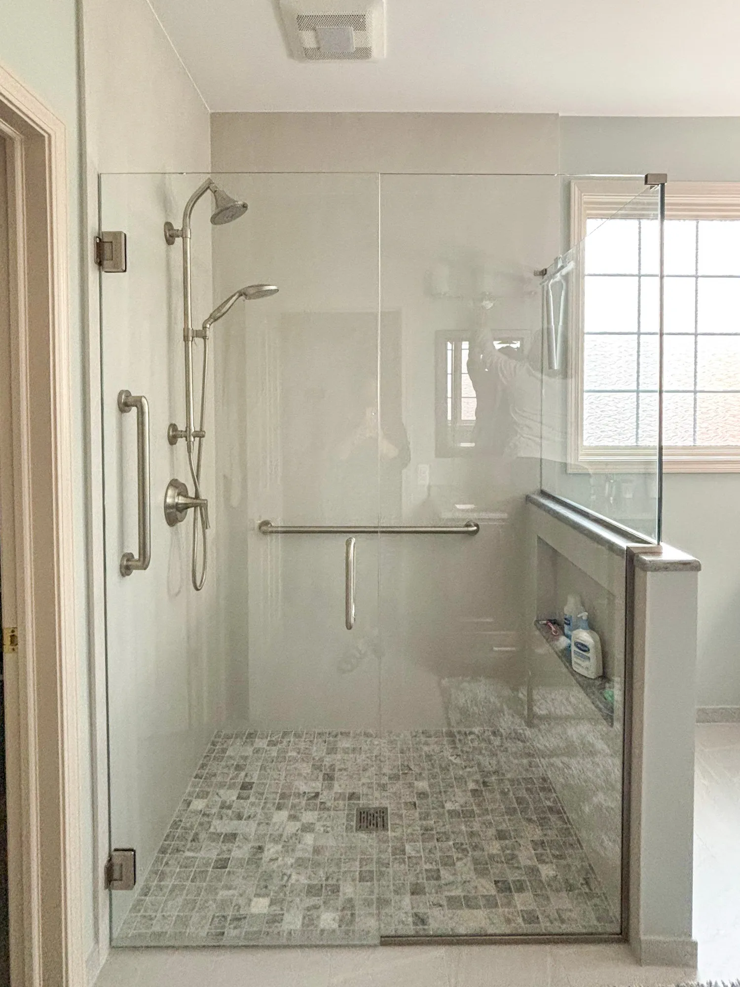 Glass shower enclosure with tiled floor and built-in shelf.
