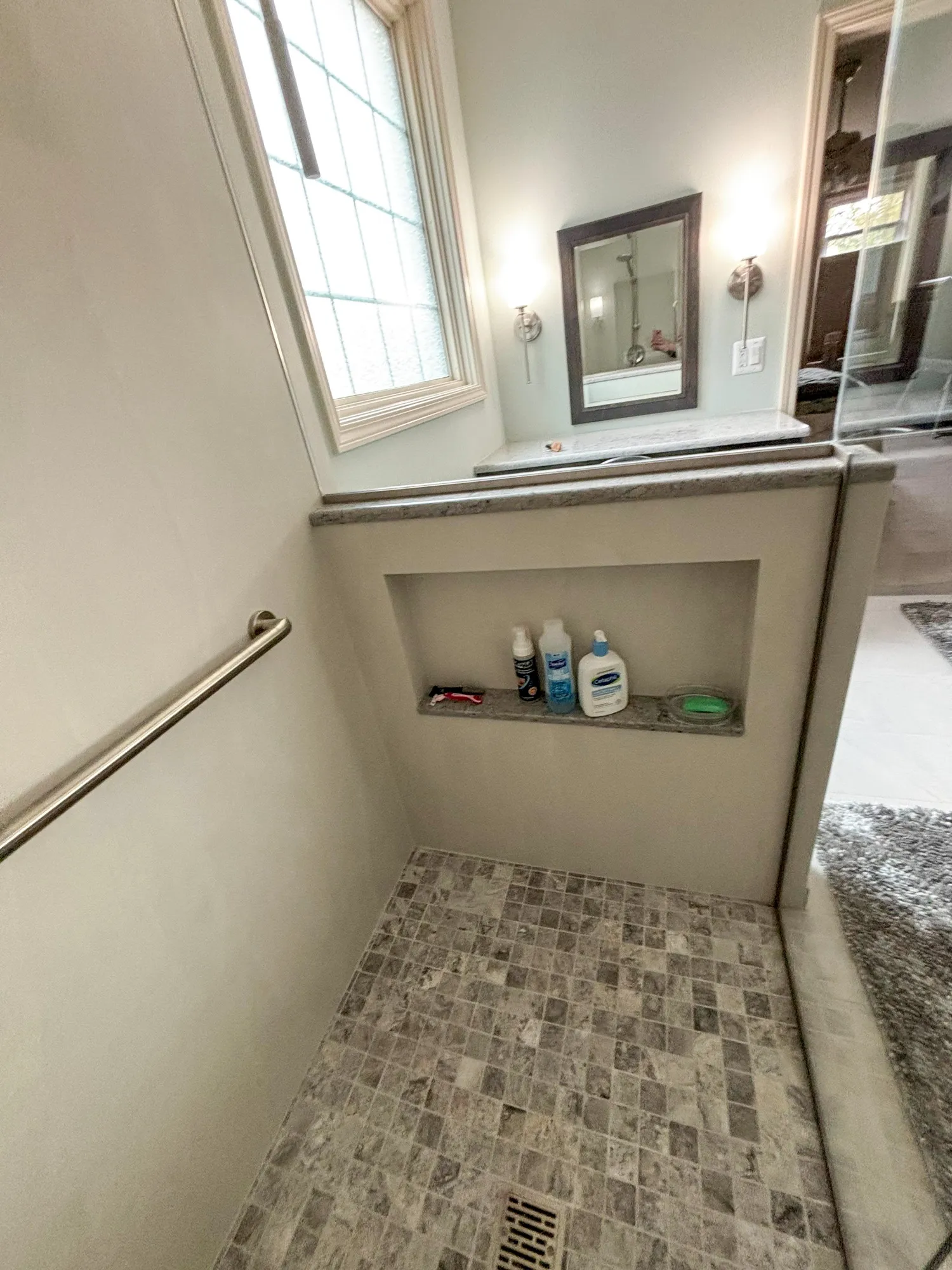 Shower area with tiled floor, built-in shelf, and toiletries