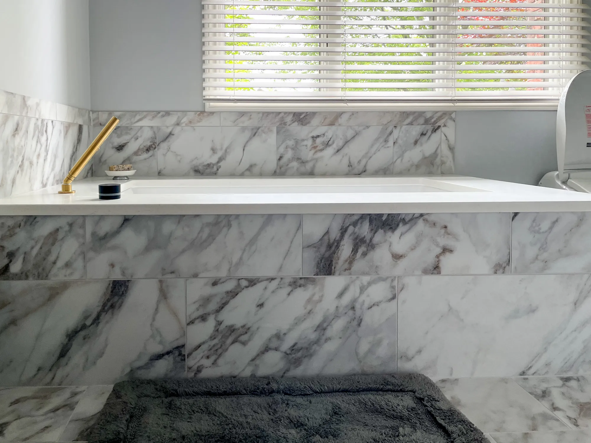 Marble bathtub with gold faucet and window blinds