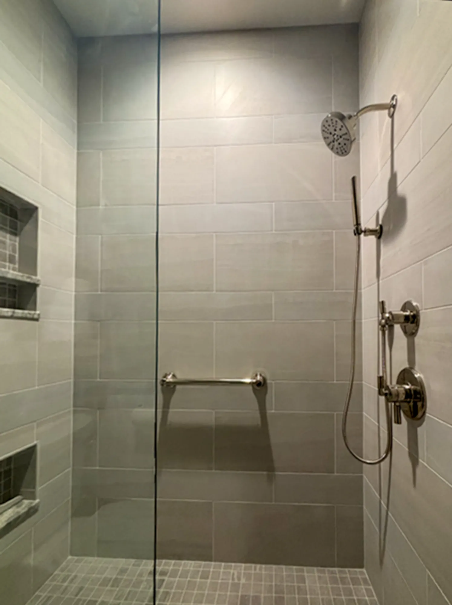 Modern bathroom shower with gray tile and glass door featuring sleek fixtures in plymouth, mi