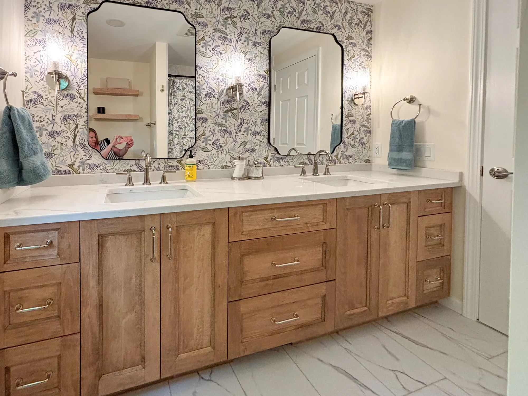 Luxury bathroom featuring a marble countertop, wooden cabinets, and floral wallpaper.