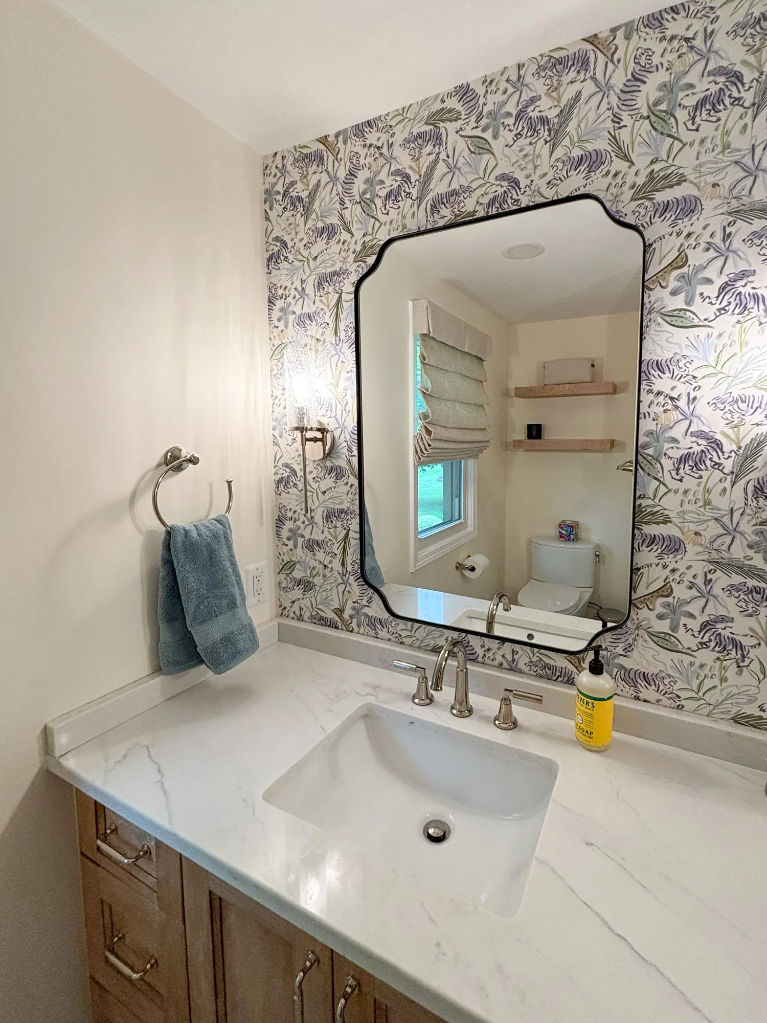 Elegant contemporary bathroom with floral wallpaper, marble countertop, and stylish mirror