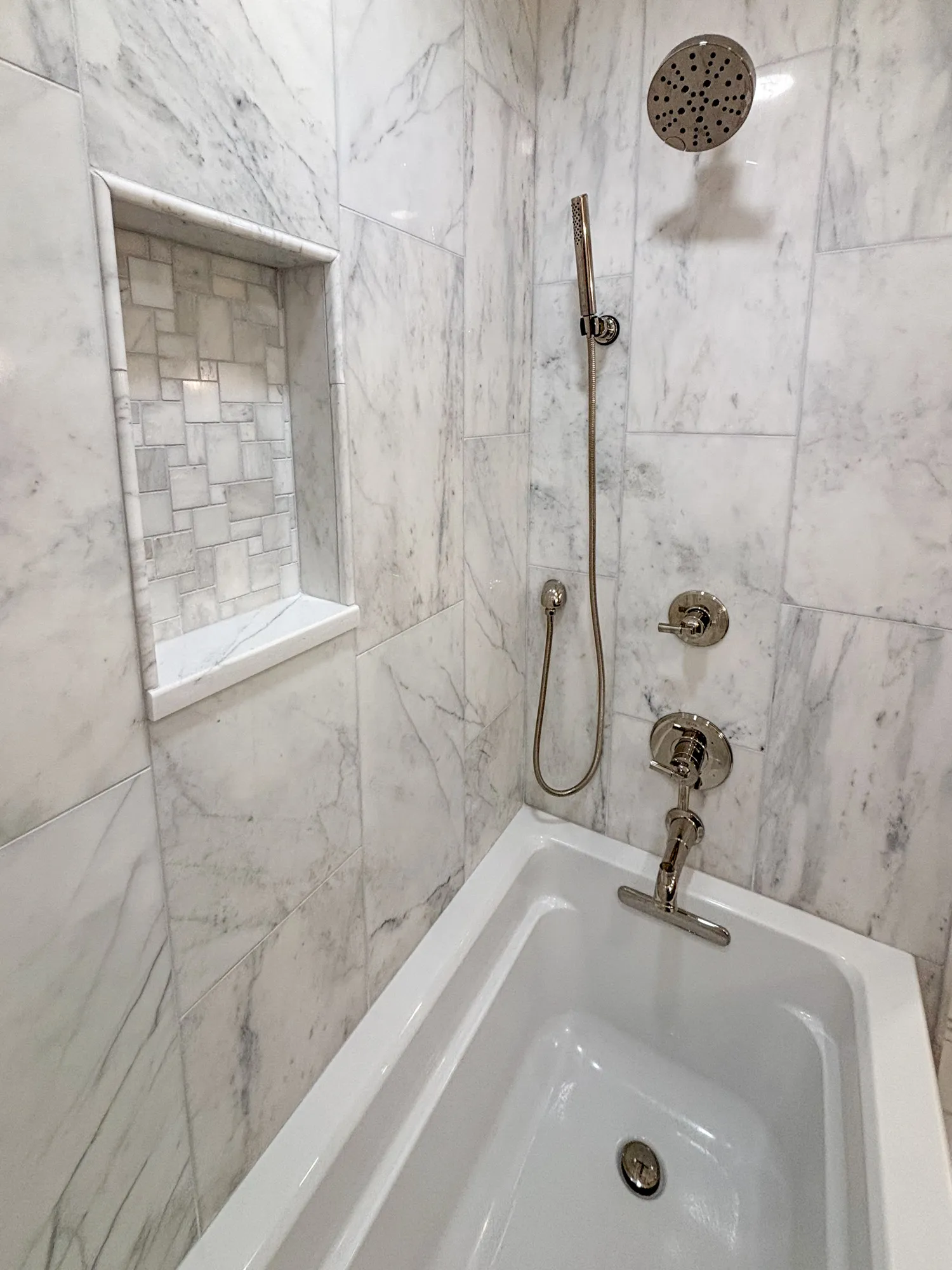 luxury bathroom with marble tiles, rainfall showerhead, and modern fixtures