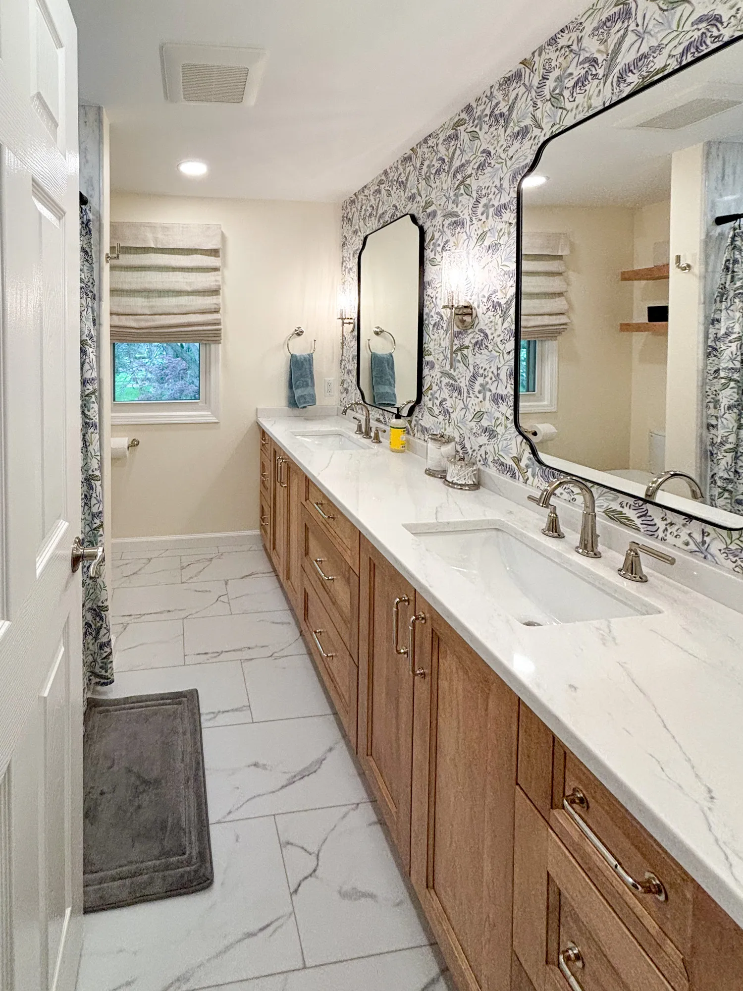 Modern bathroom with wood cabinets, marble countertop, and floral wallpaper, enhancing serenity