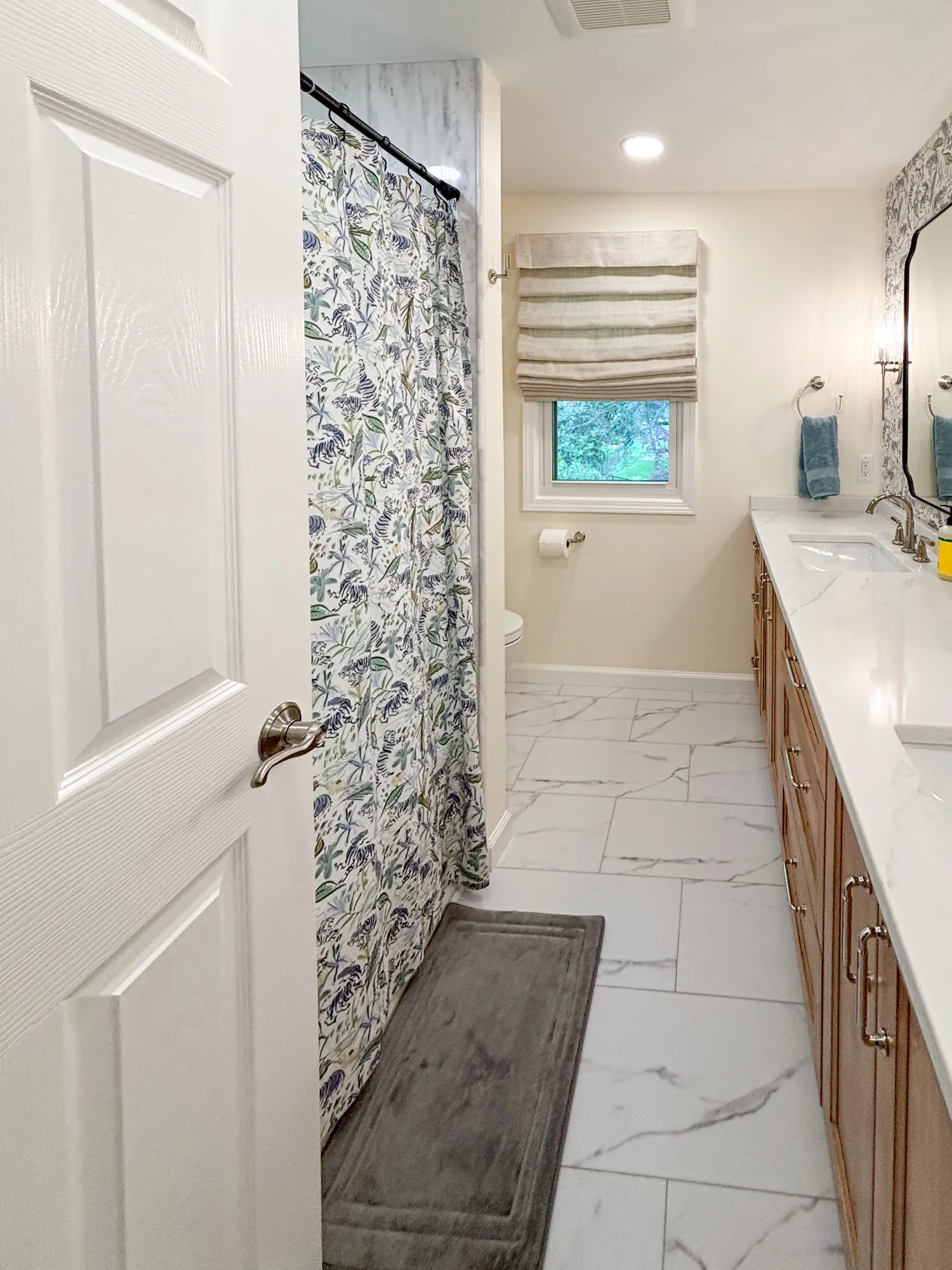 Elegant bathroom with floral shower curtain, marble tile floor, and wooden vanity