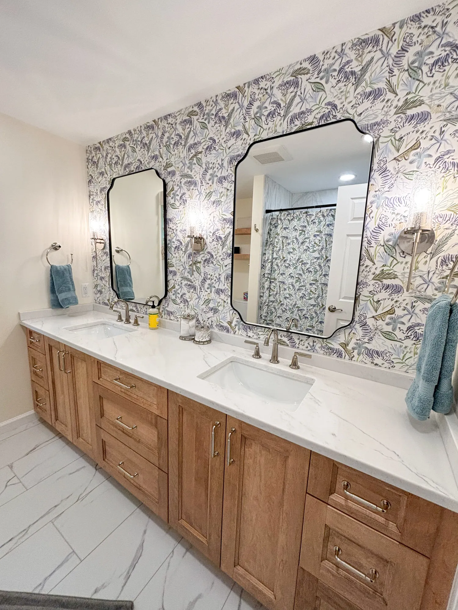 Elegant modern bathroom featuring a double vanity with marble countertops and floral wallpaper.