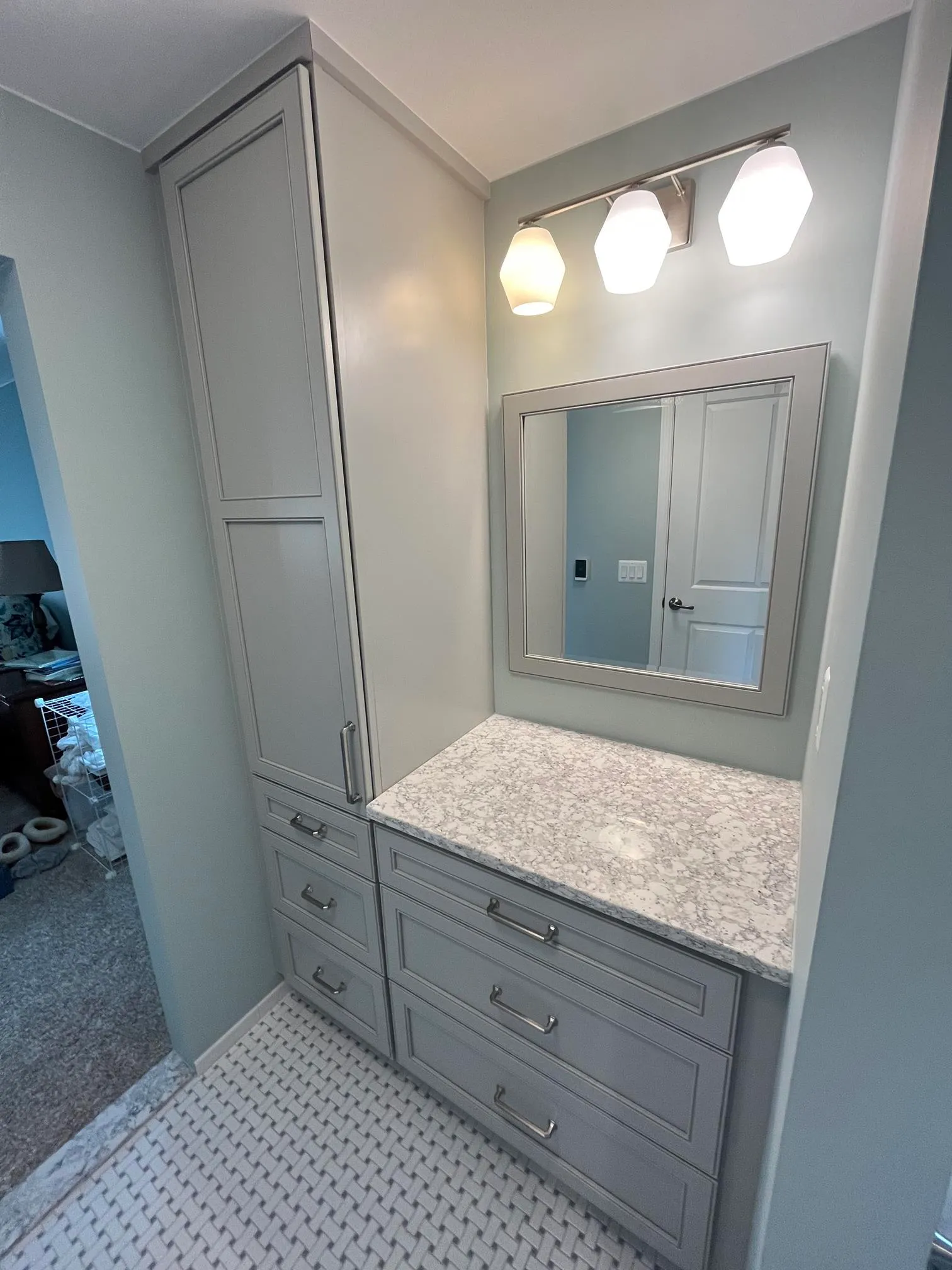Contemporary bathroom with gray cabinetry, marble countertop, and hexagon lighting.