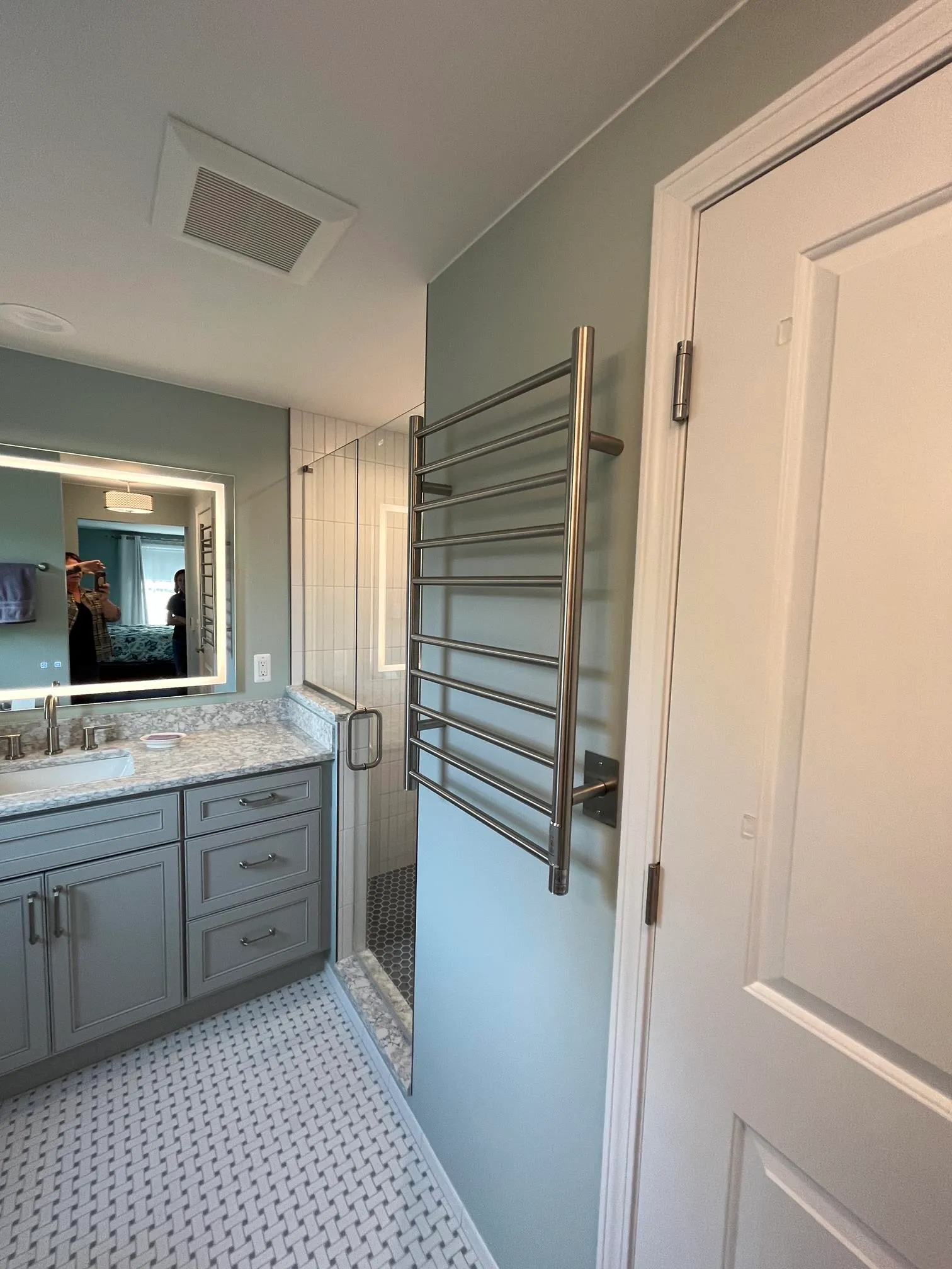 Luxury bathroom with blue walls, marble countertop, and towel warmer in a contemporary style