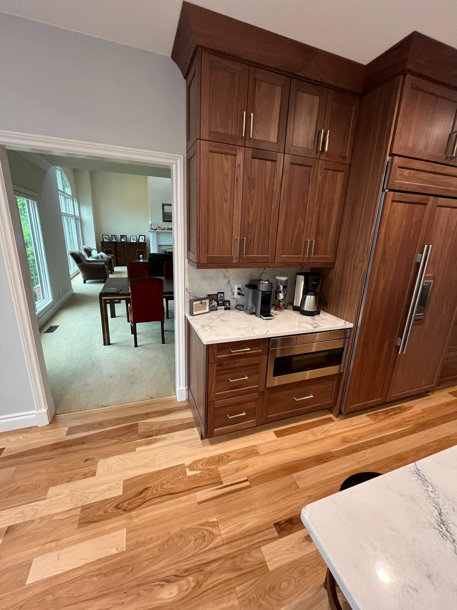 Modern kitchen in plymouth, michigan with walnut cabinets, marble countertops, and hardwood flooring