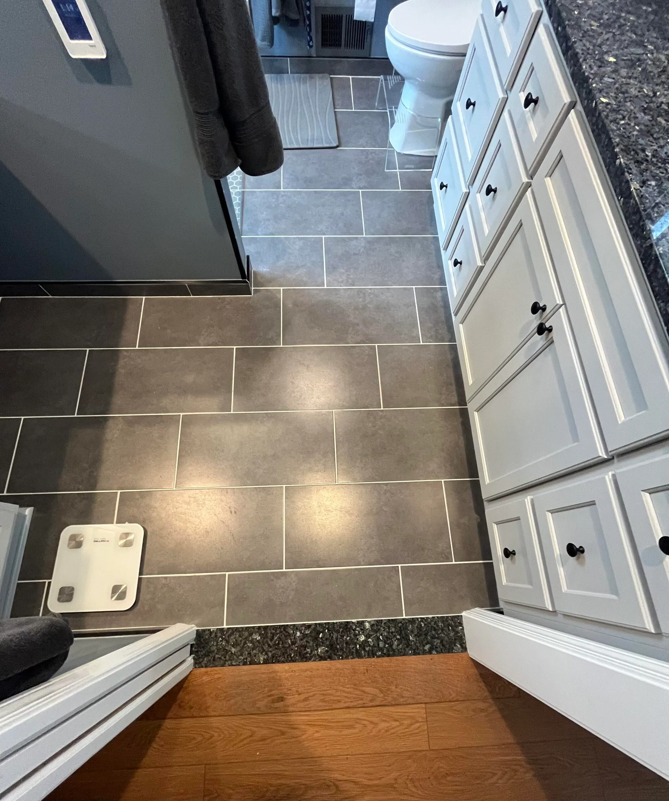Modern bathroom with gray tile floor and white cabinetry, featuring a touch of elegance and functionality