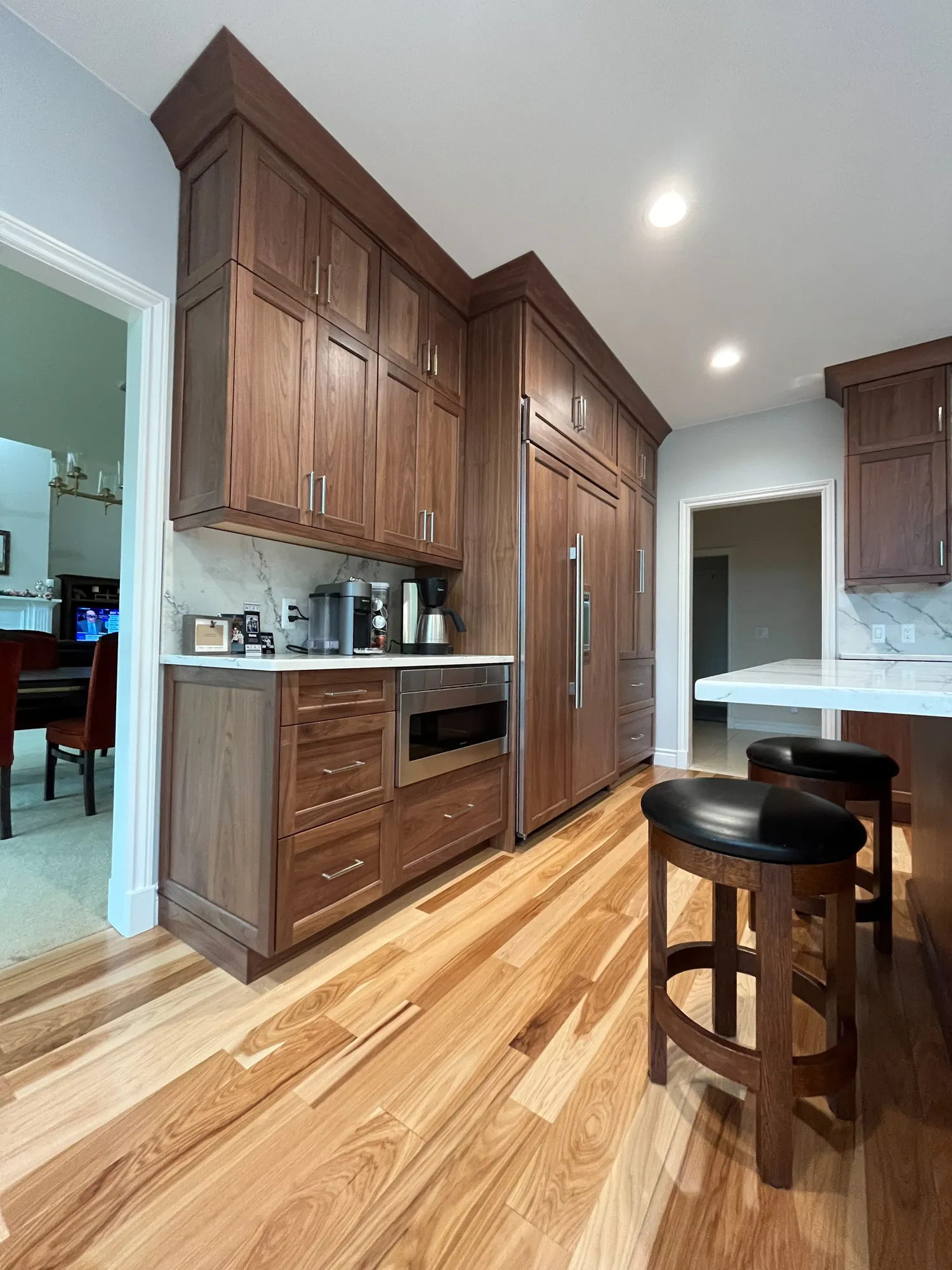 Modern kitchen in plymouth, michigan featuring walnut cabinetry and a sleek island with black stools