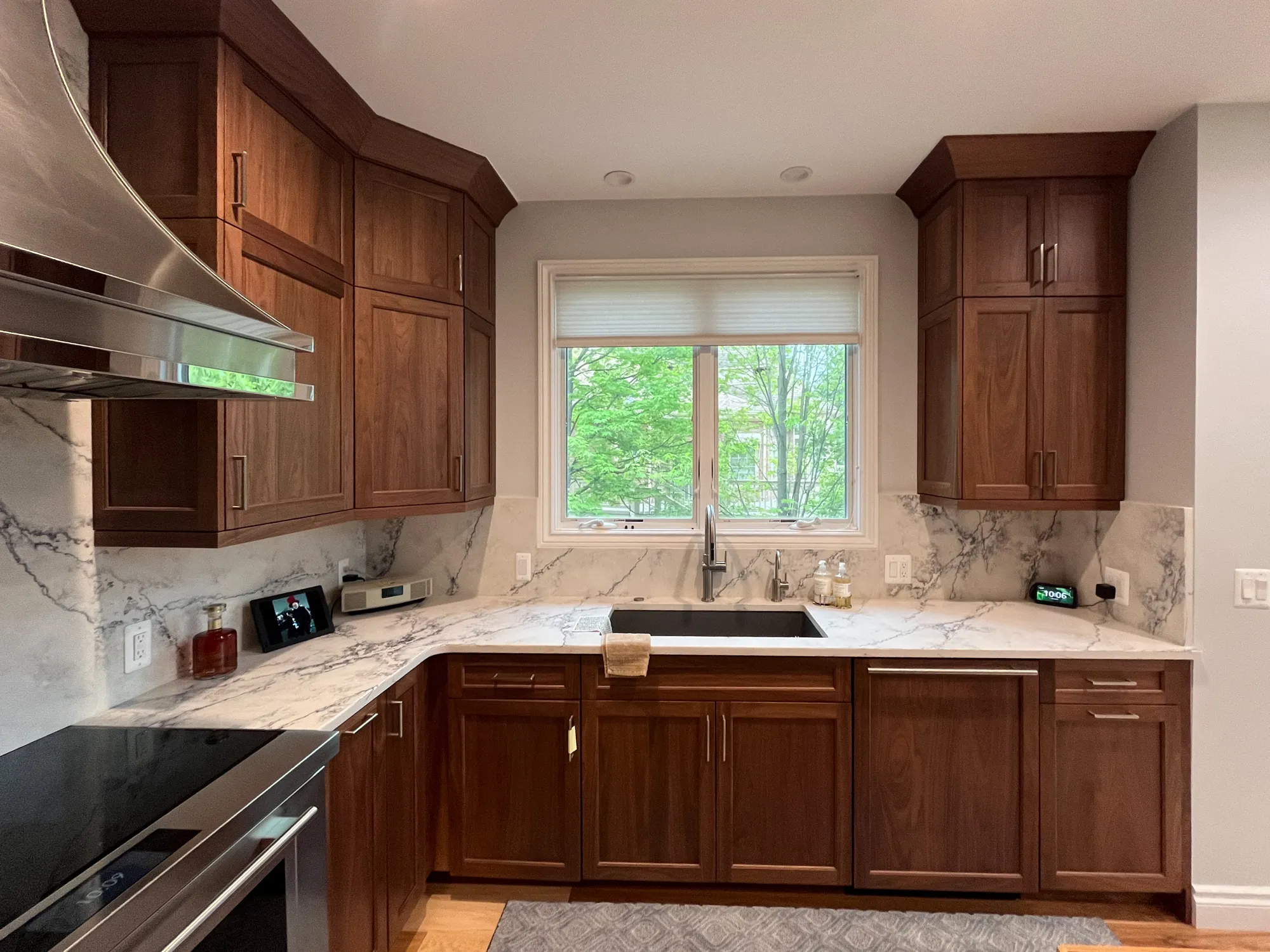 Modern kitchen in plymouth michigan featuring walnut cabinets, marble countertops, and a window view.