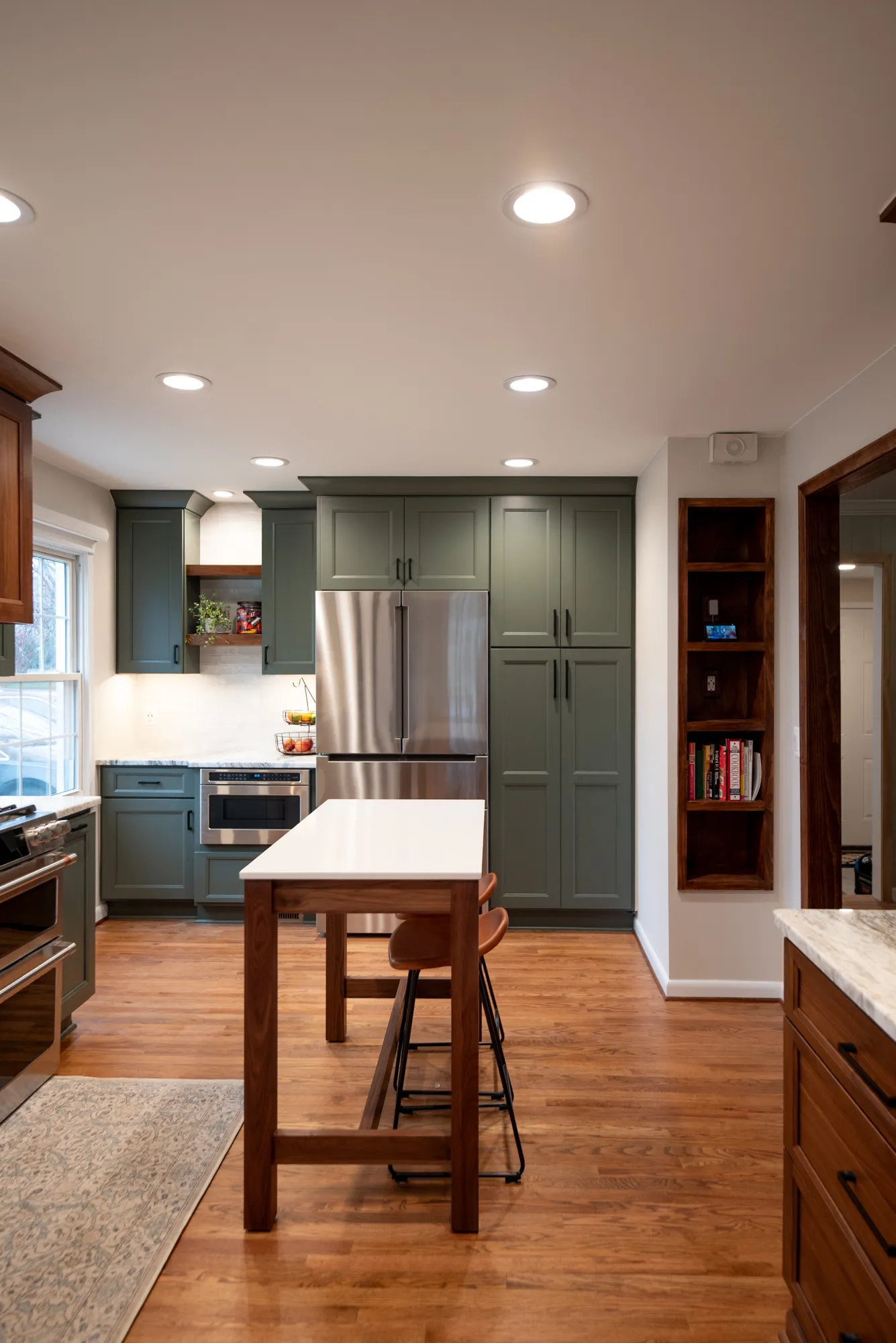 Modern kitchen featuring green cabinets, stainless steel appliances, and a white countertop in a contemporary style.