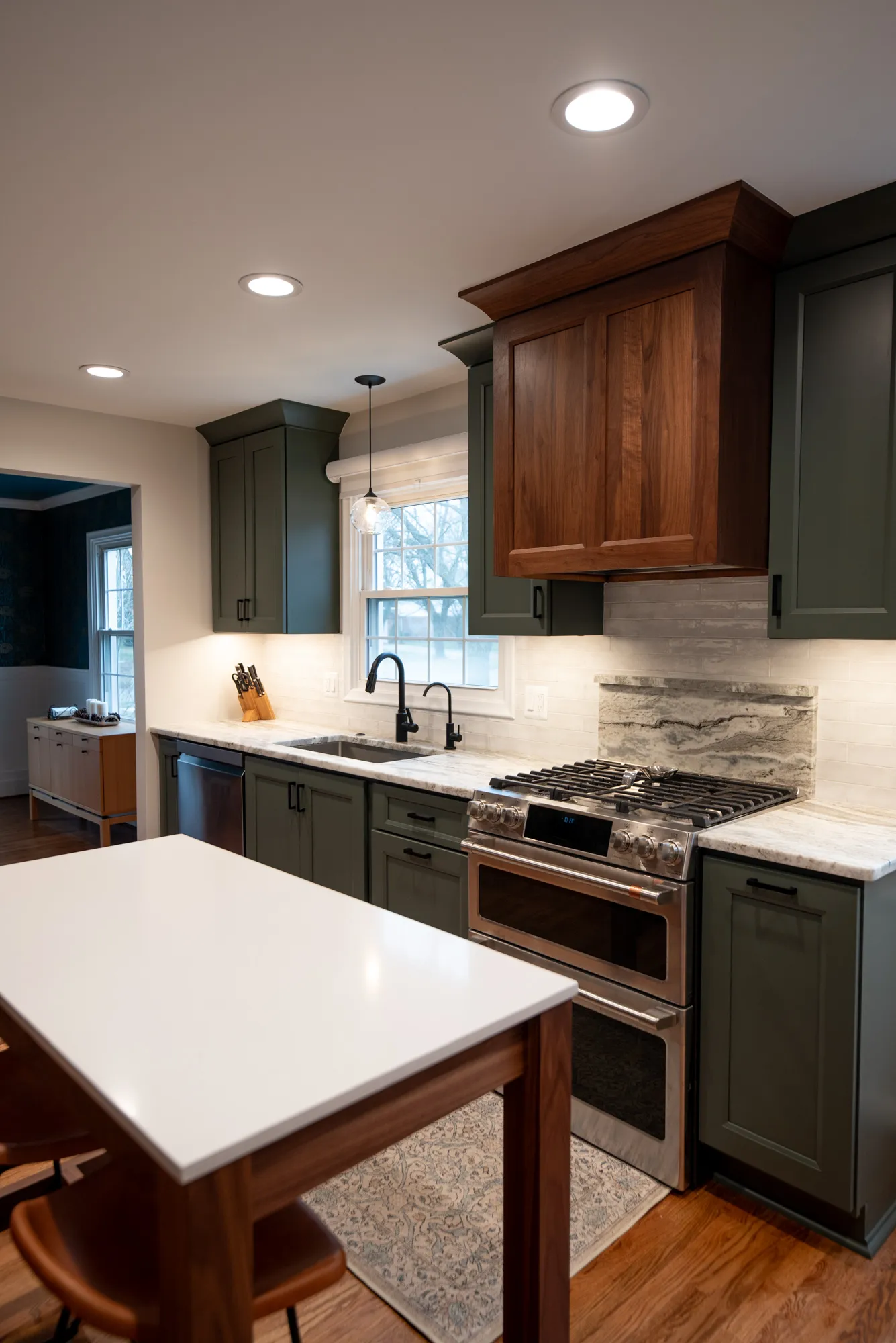 Modern kitchen featuring green cabinetry, a gas range, and white marble countertop.