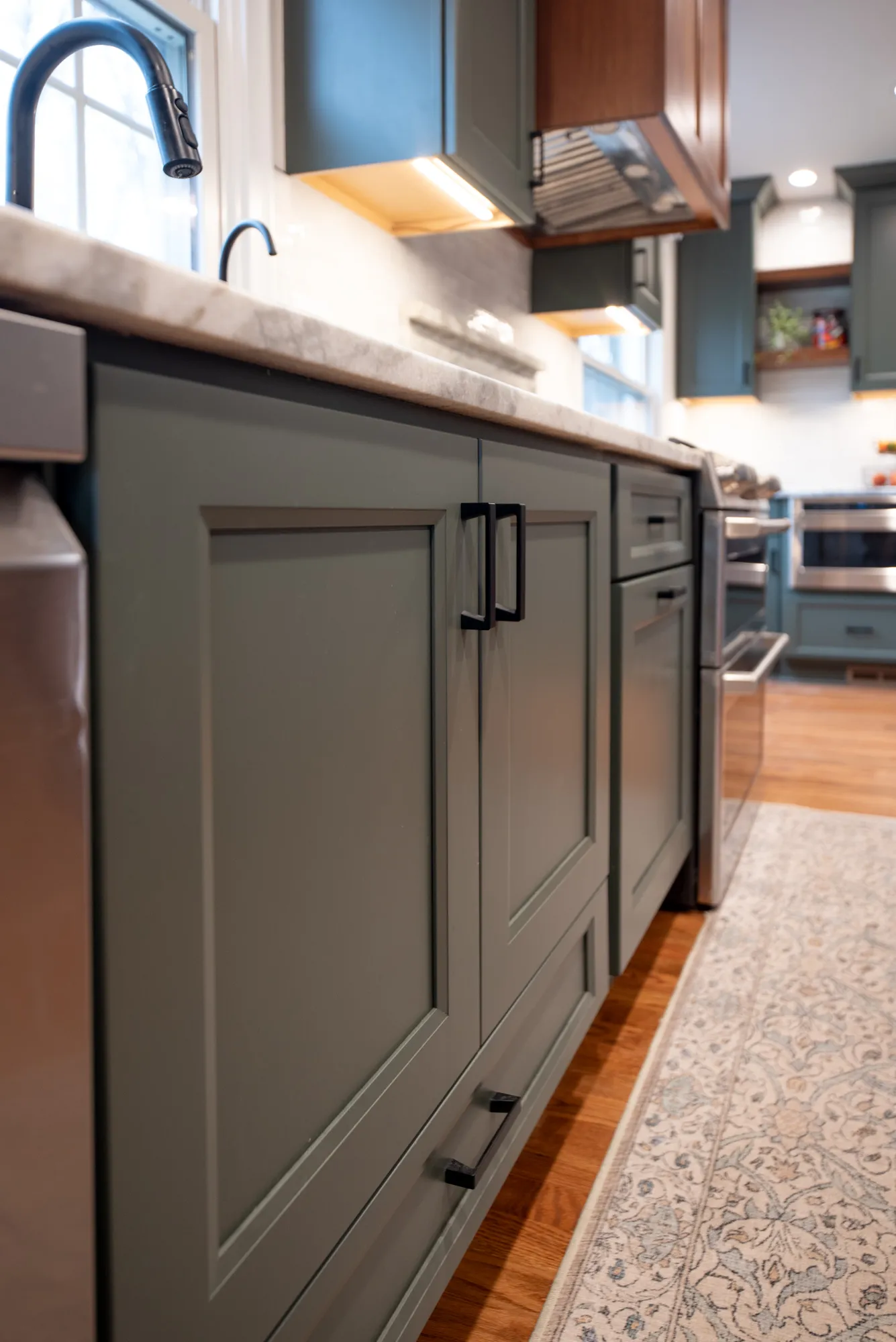 Modern kitchen with gray cabinetry and marble countertop features elegant black fixtures for a stylish design.