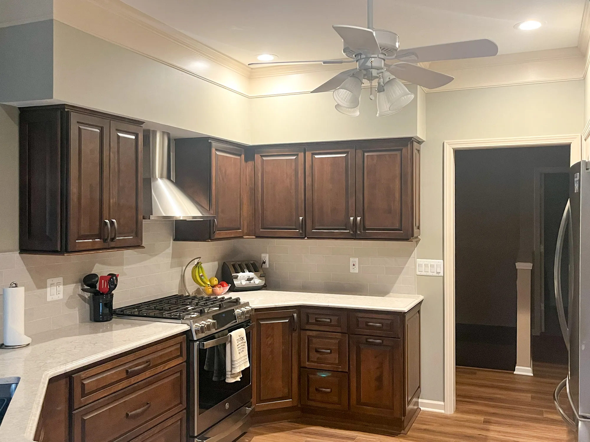 Modern kitchen featuring dark wood cabinets, stainless steel appliances, and light gray tile backsplash in plymouth, michigan.