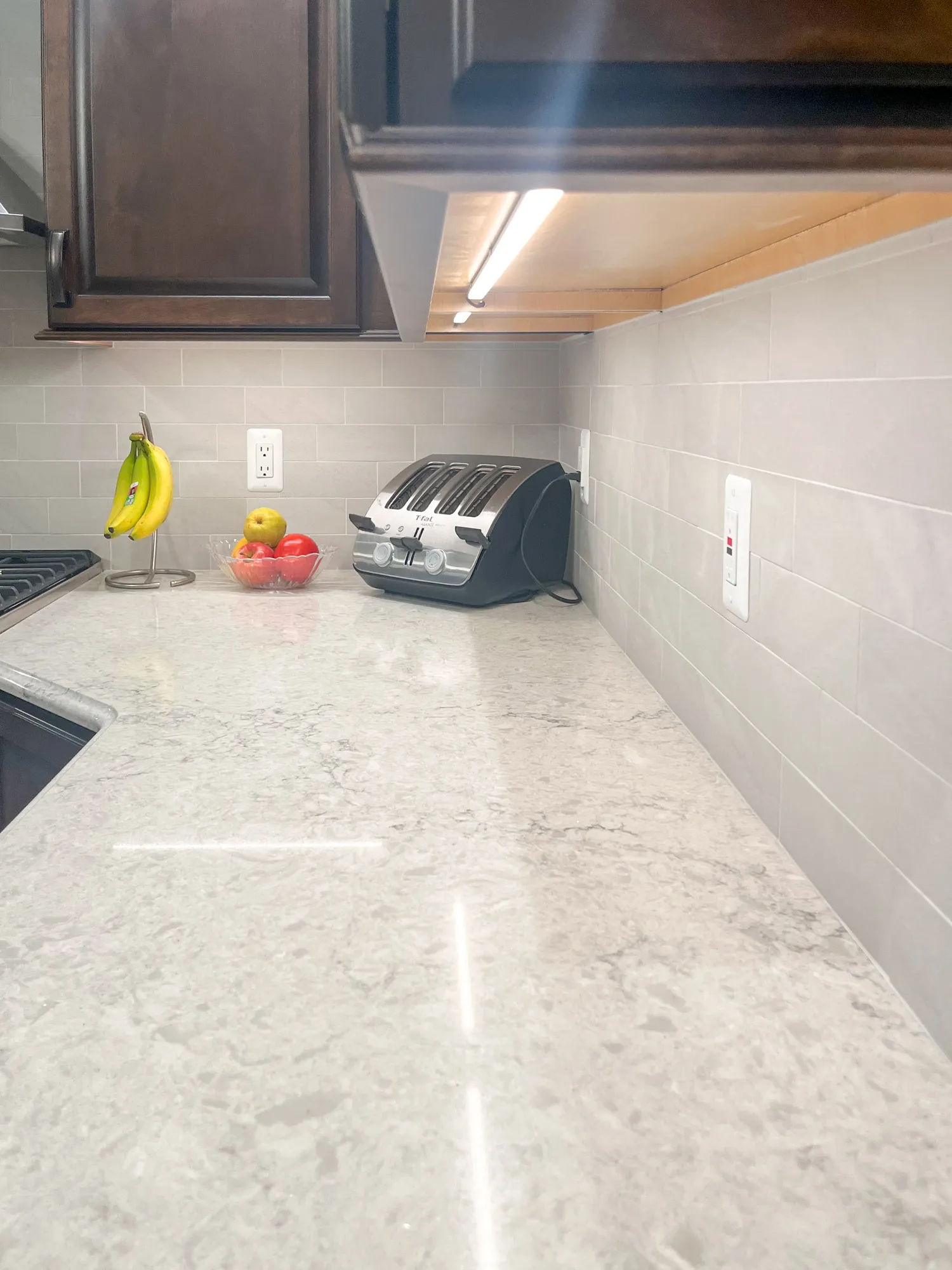 Modern kitchen renovation in plymouth featuring gray stone countertop, dark wood cabinets, and sleek appliances.