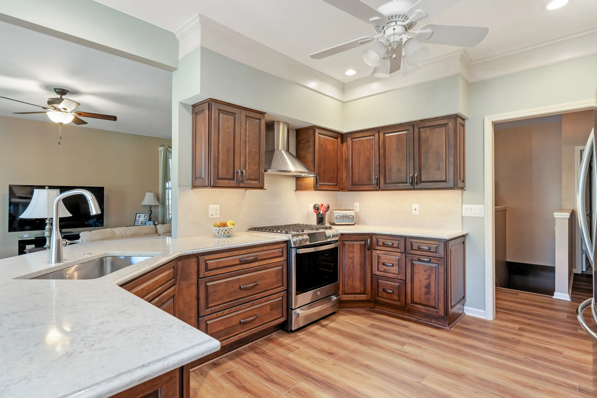 Modern kitchen renovation in Plymouth, Michigan featuring dark wood cabinetry, stainless steel appliances, and a marble countertop.