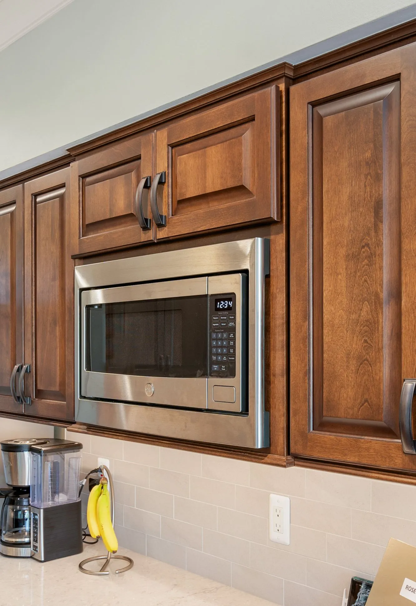 Modern kitchen in plymouth, michigan featuring sleek cabinetry, stainless steel microwave, and a coffee maker.