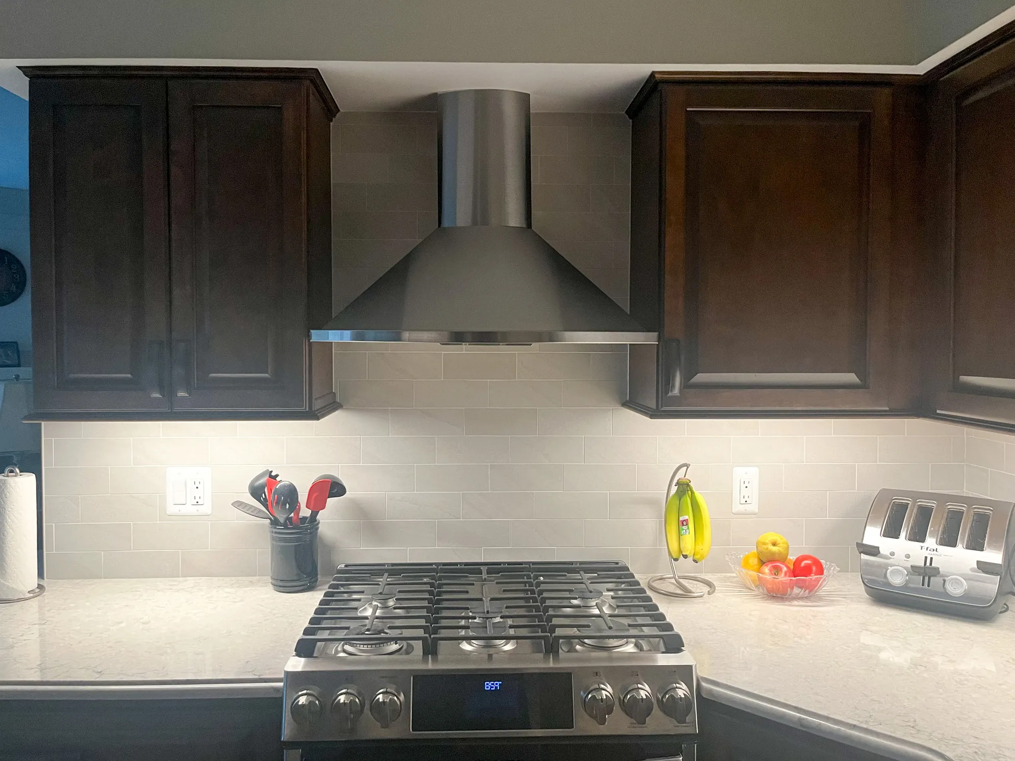 Modern kitchen with dark wood cabinets, stainless steel hood range, and marble countertop in plymouth, michigan