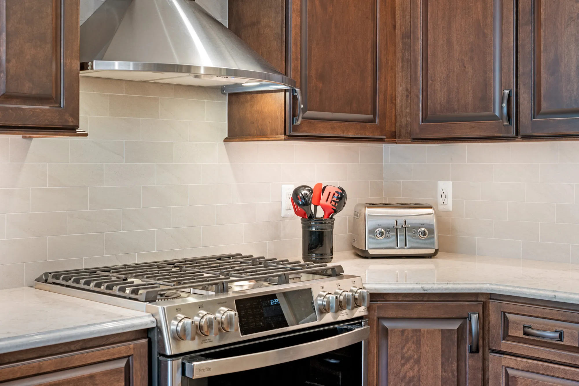 Modern kitchen renovation featuring a gas stove, wooden cabinets, and a stylish backsplash in plymouth, michigan.
