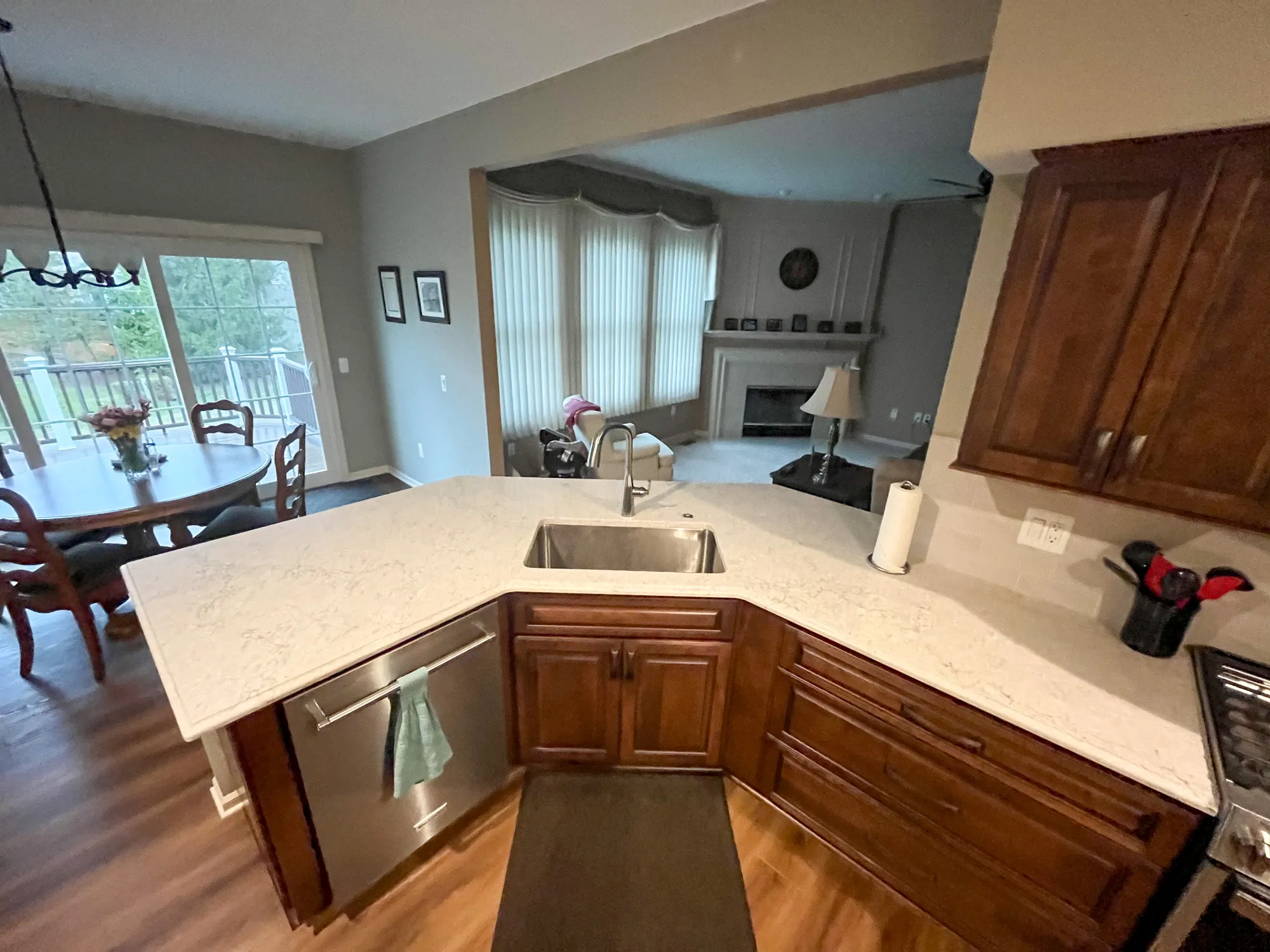 Modern kitchen in plymouth, michigan featuring a quartz countertop, dark wood cabinets, and an open layout to a living area.