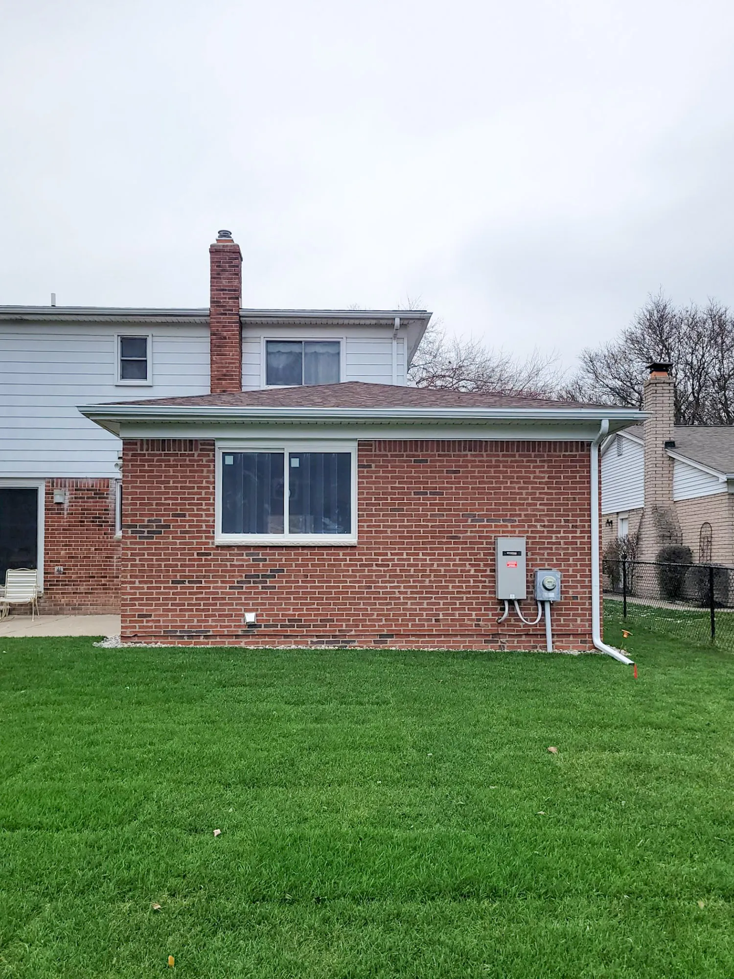 Brick exterior of a modern home with a green lawn and a gray sky