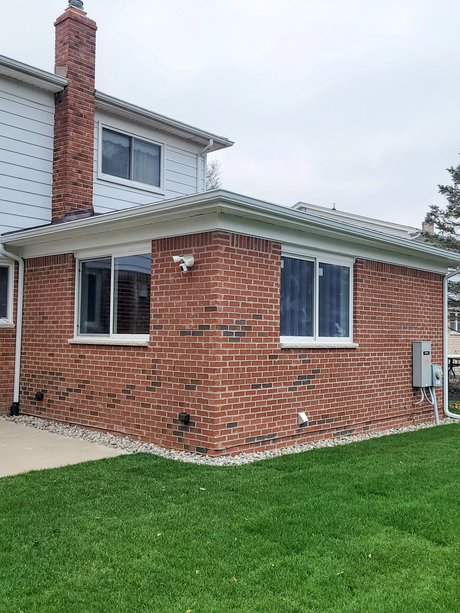 Modern exterior view of a brick home with large windows and a chimney in a grassy yard