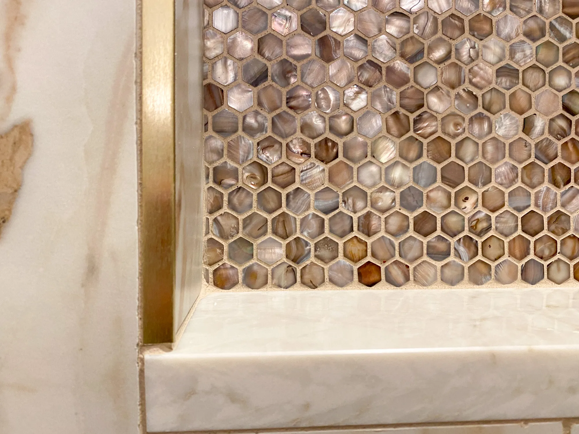 Modern bathroom with hexagonal shell tile backsplash and polished marble countertop