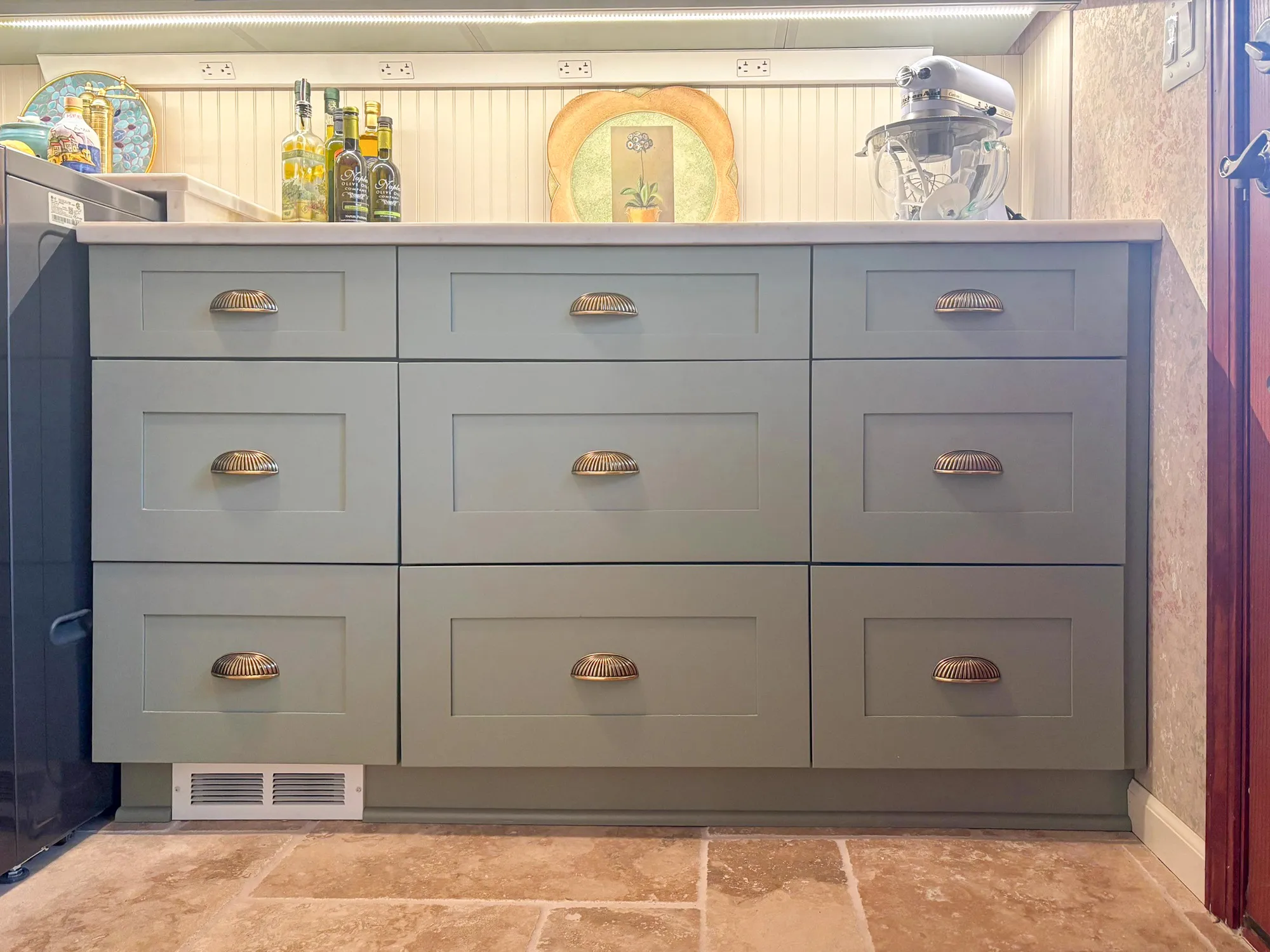 Contemporary kitchen with gray cabinetry featuring gold shell handles and decorative elements in a stylish design.