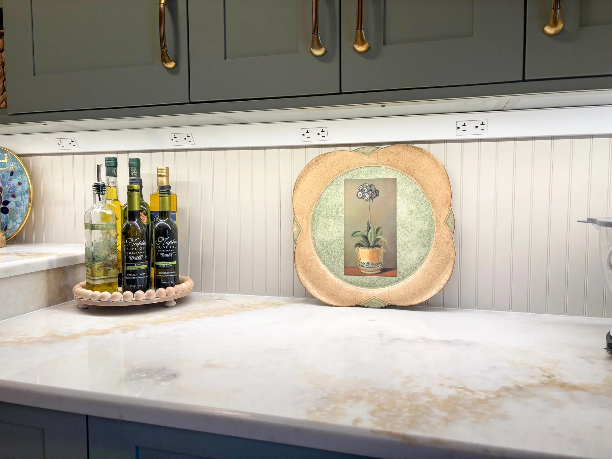 Modern kitchen countertop featuring olive oil bottles, a decorative plate, and a marble surface