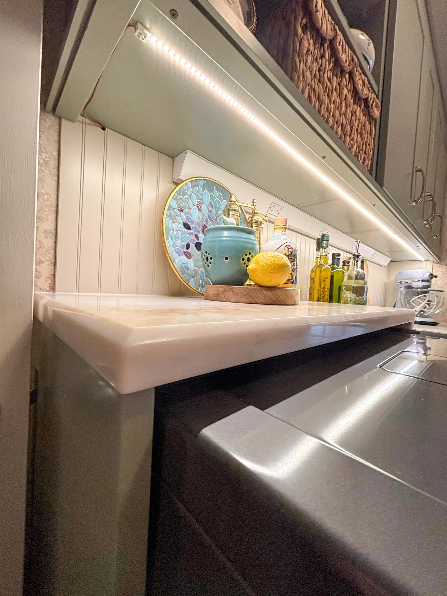 Charming contemporary kitchen with marble countertop, teal pottery, and ambient lighting