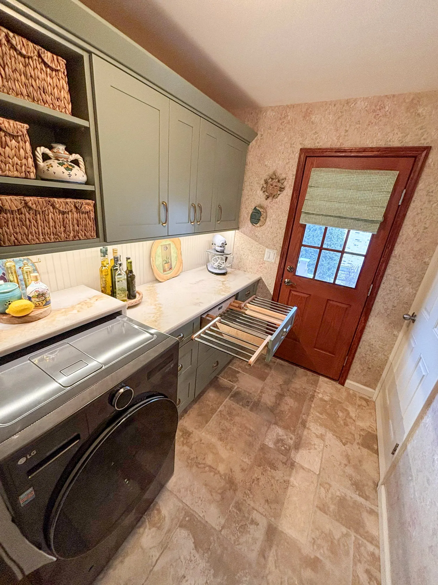 Modern laundry room featuring gray cabinets, a washing machine, and a wooden door, designed for functionality and style.