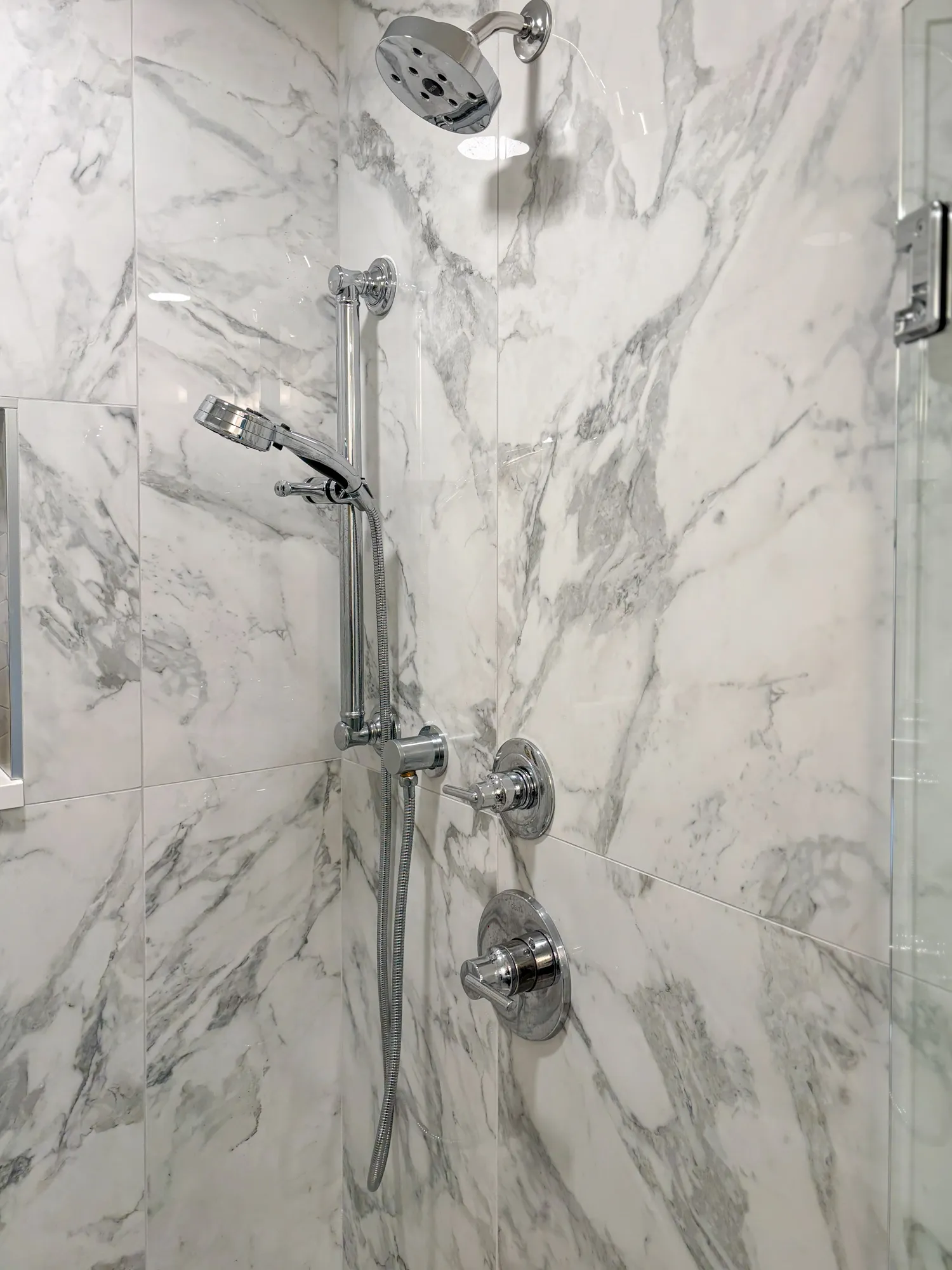 Luxury bathroom shower with chrome fixtures and marble walls, offering a modern shower experience.