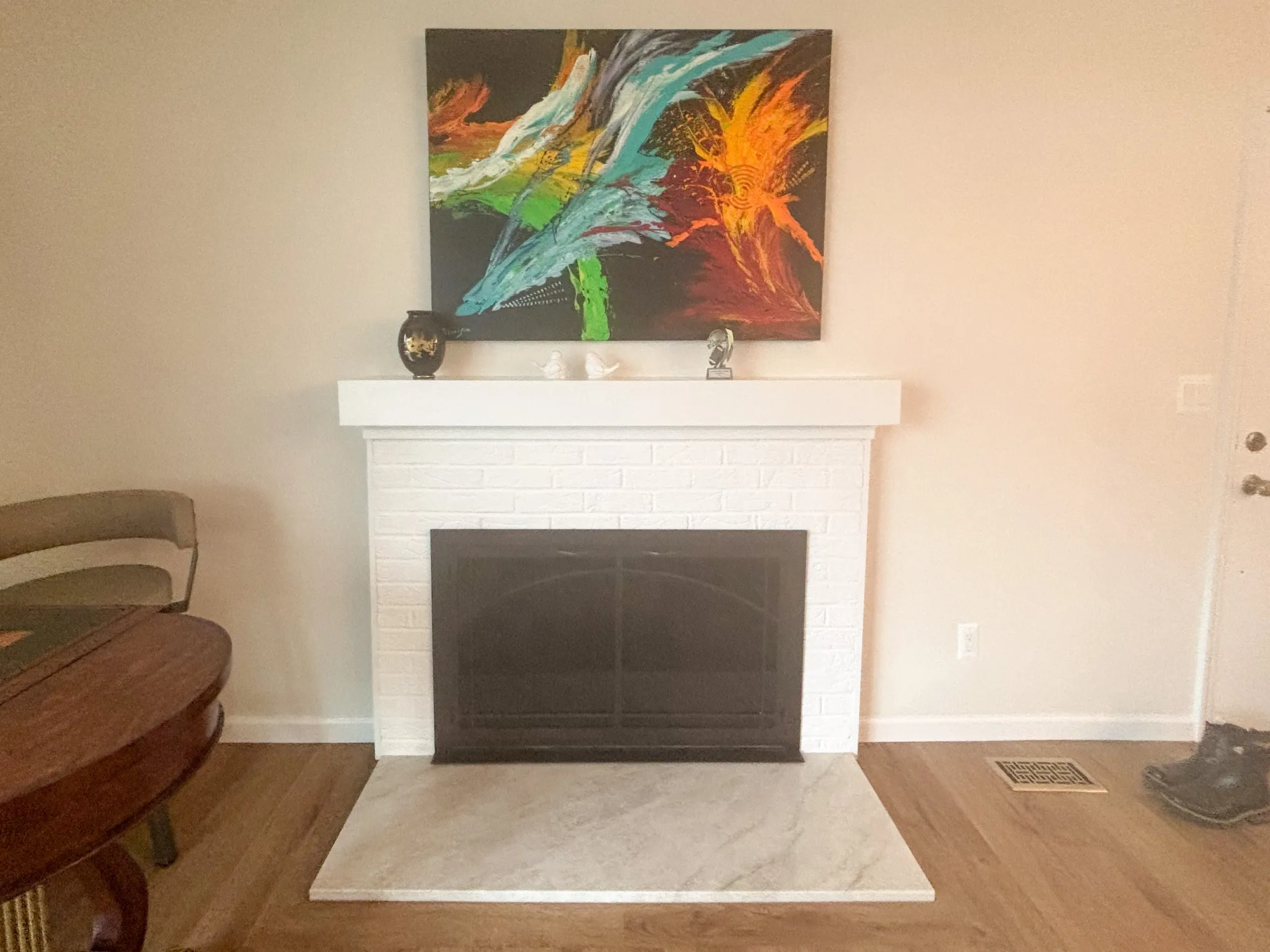 Modern living room featuring a white-brick fireplace and colorful abstract art, emphasizing comfort and style.