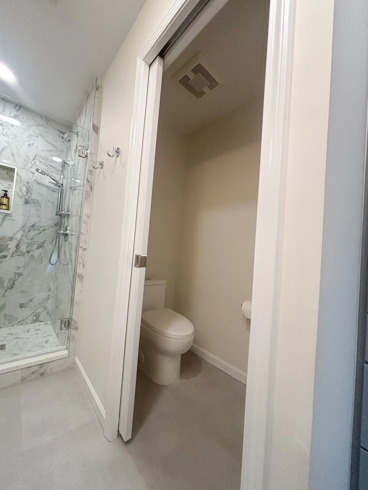 Modern bathroom featuring a glass shower and minimalist toilet, designed with white and gray tones.