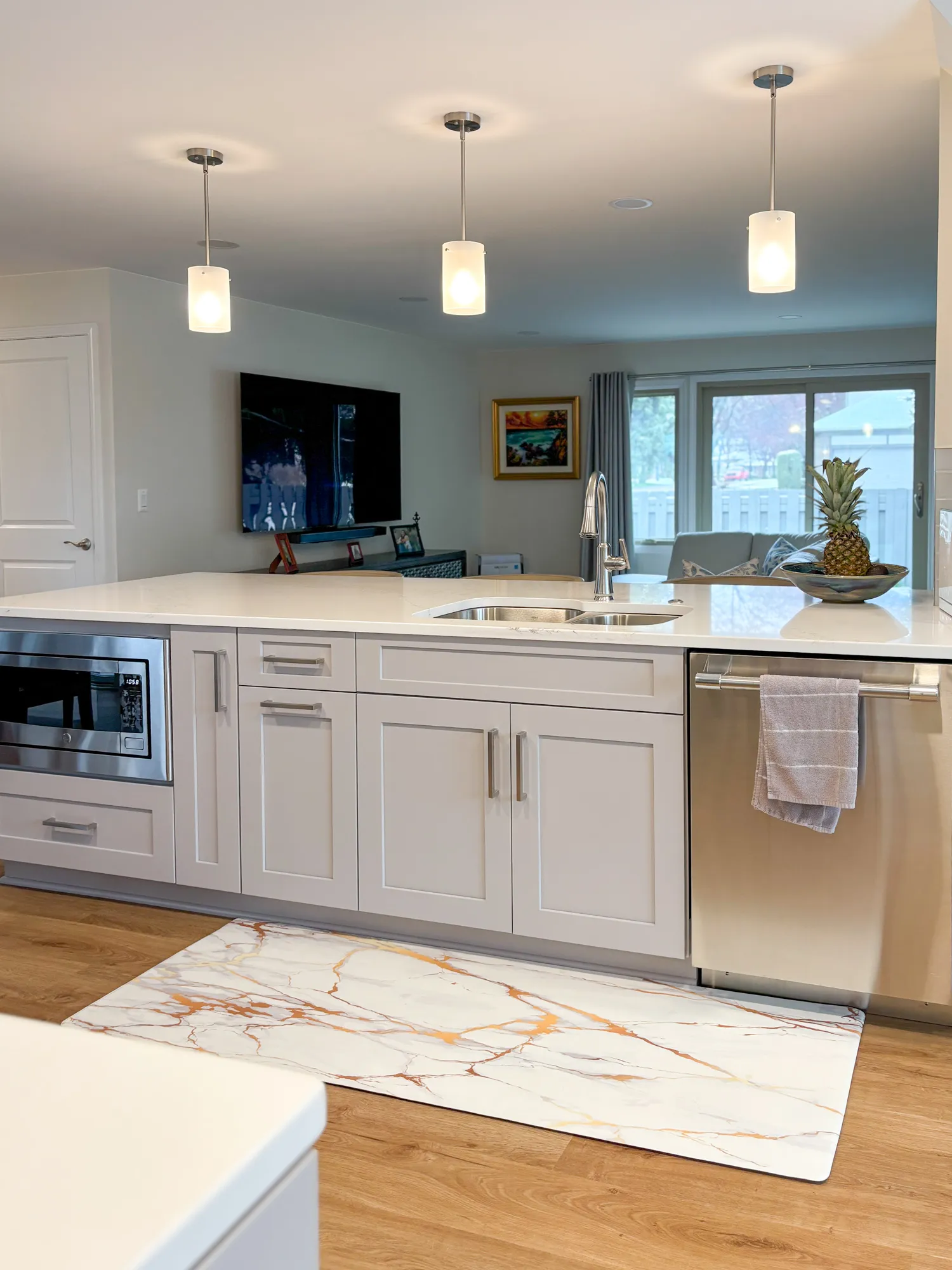 Contemporary kitchen with gray cabinets, quartz countertops, pendant lights, and a marble accent rug.