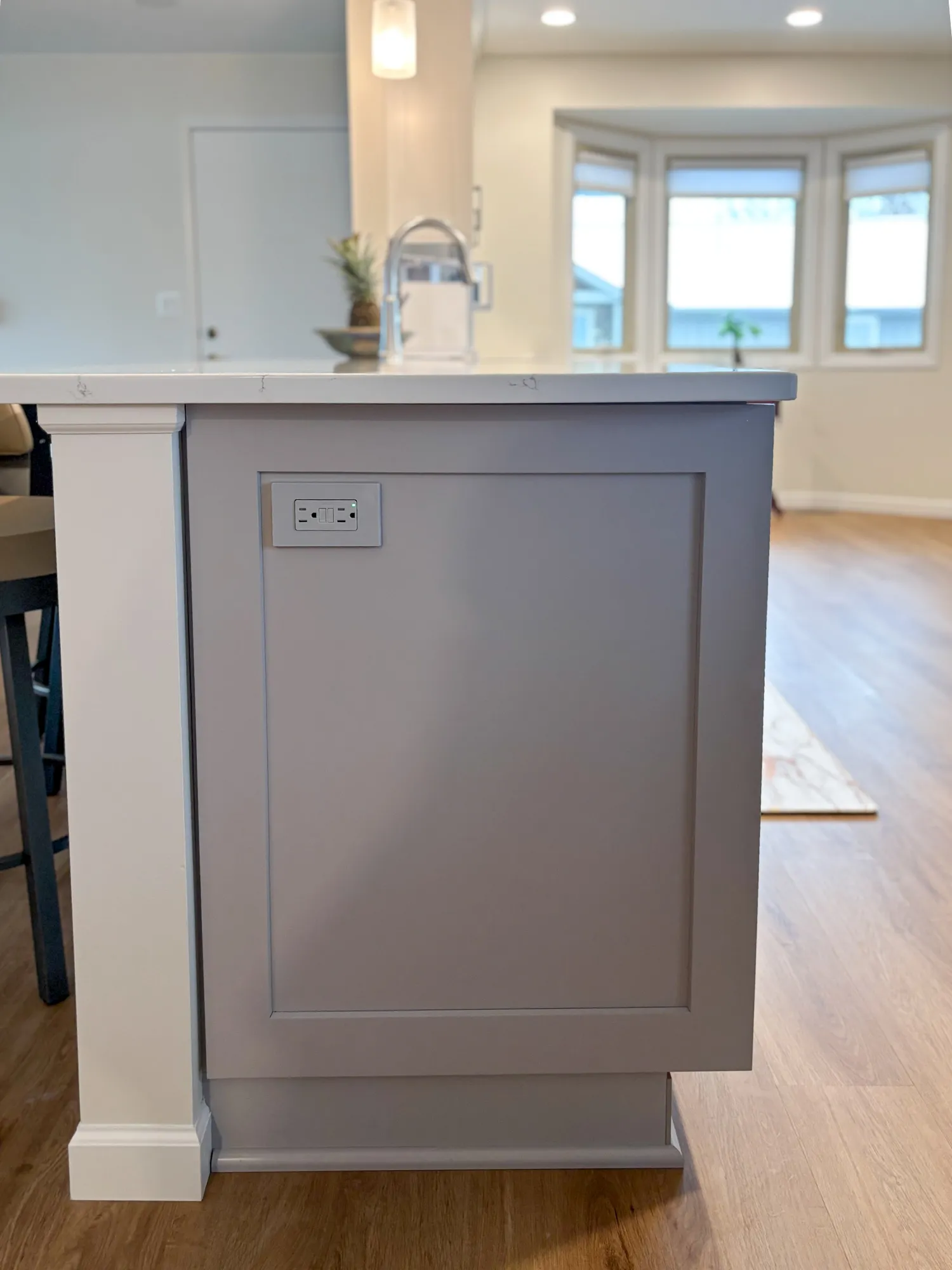 Modern kitchen island with gray cabinetry featuring electrical outlets and a white countertop