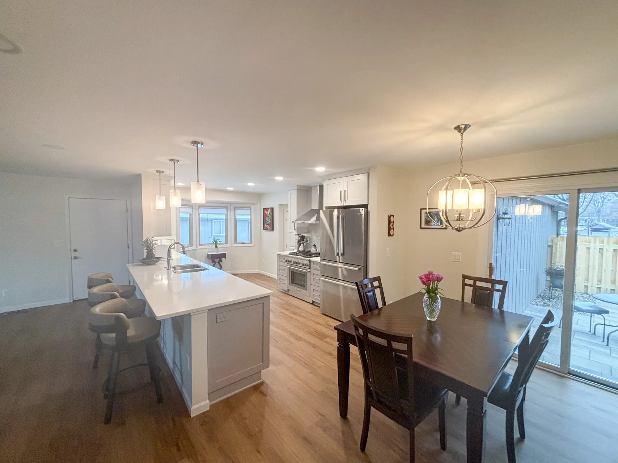 Modern kitchen and dining area with white quartz island, dark wood dining table, and pendant lights in a cozy space.