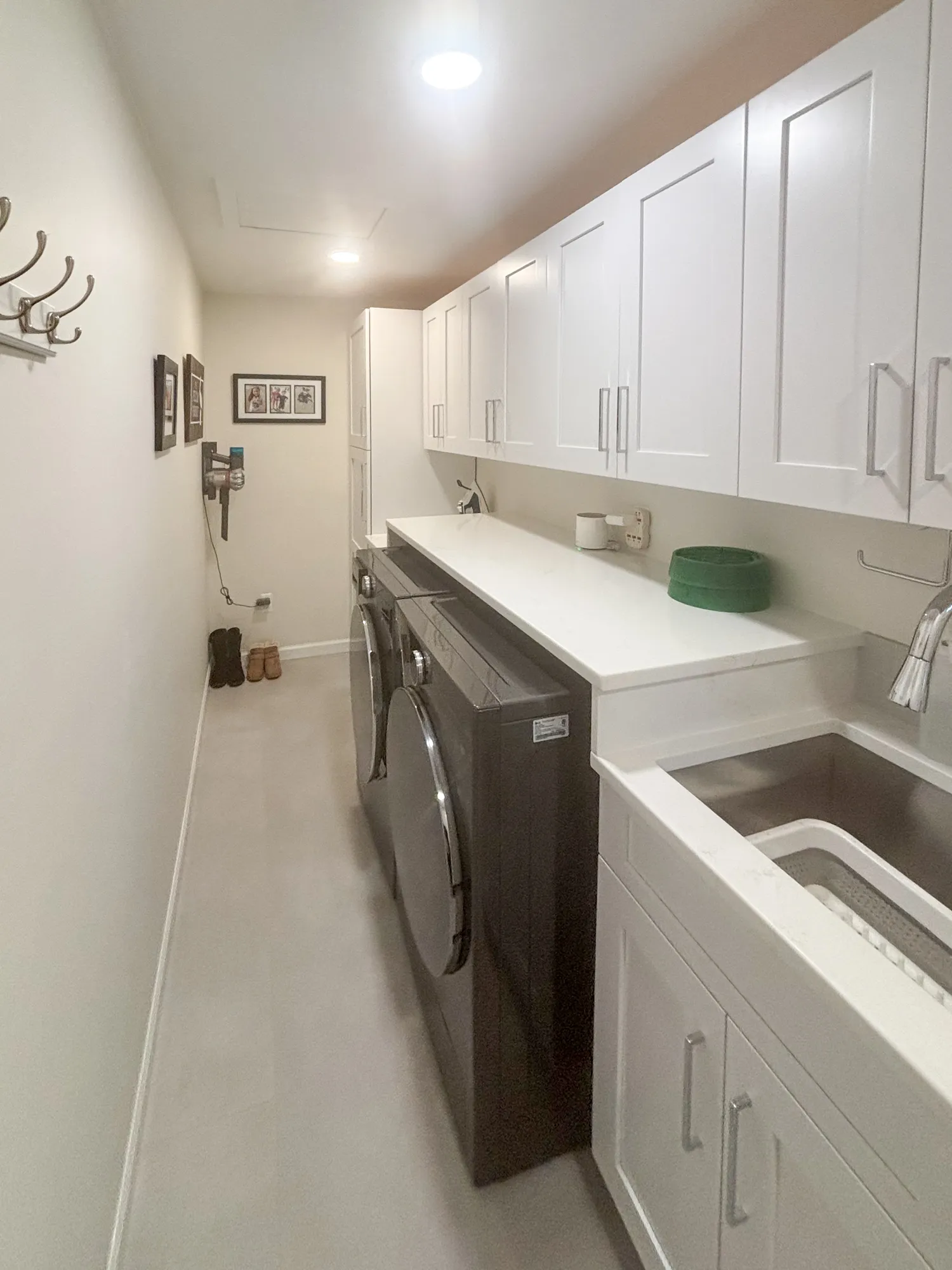 Modern laundry room with white cabinets, dark appliances, and a utility sink