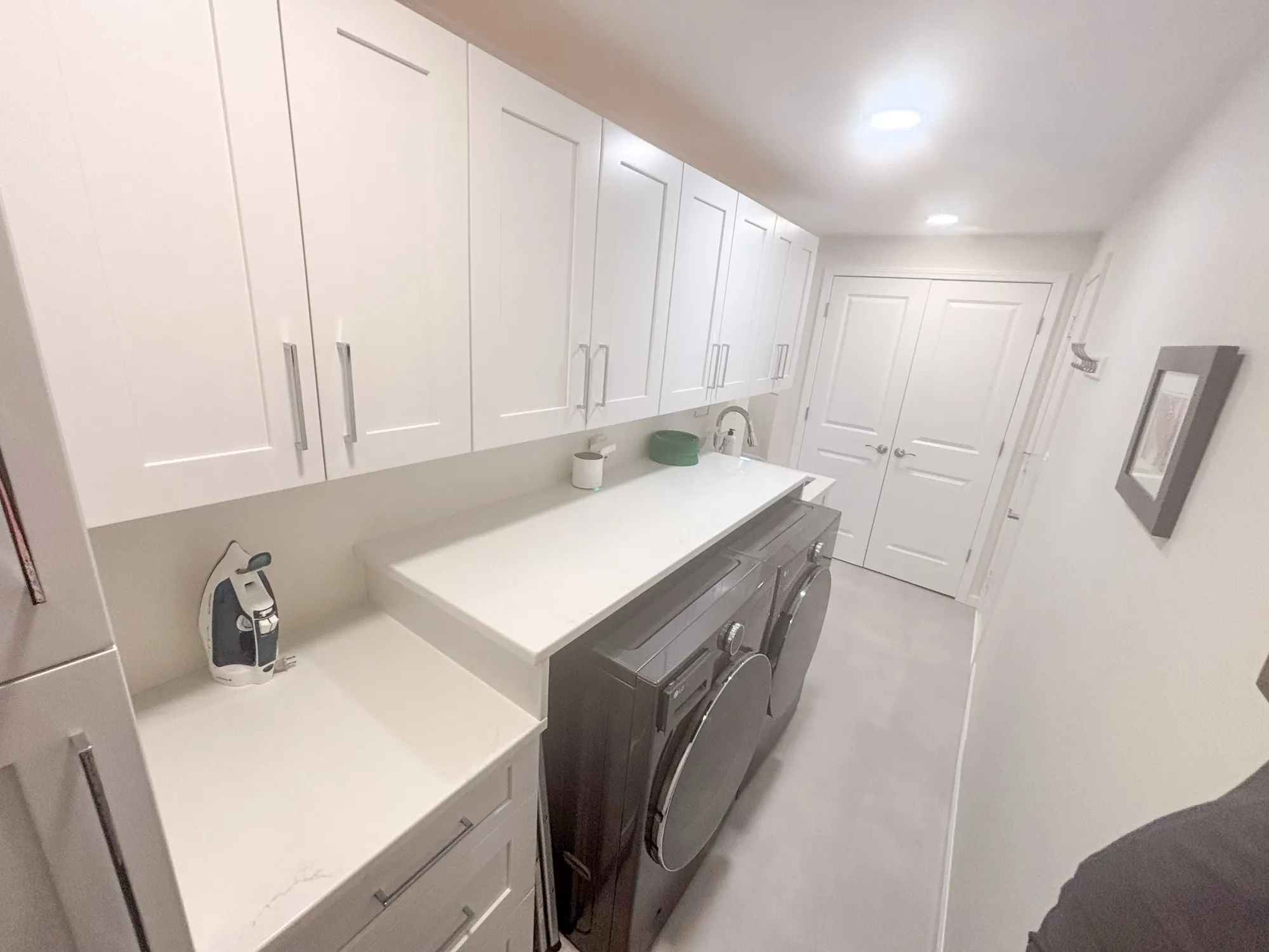 Contemporary laundry room featuring sleek white cabinetry, gray appliances, and a clean, minimalistic design