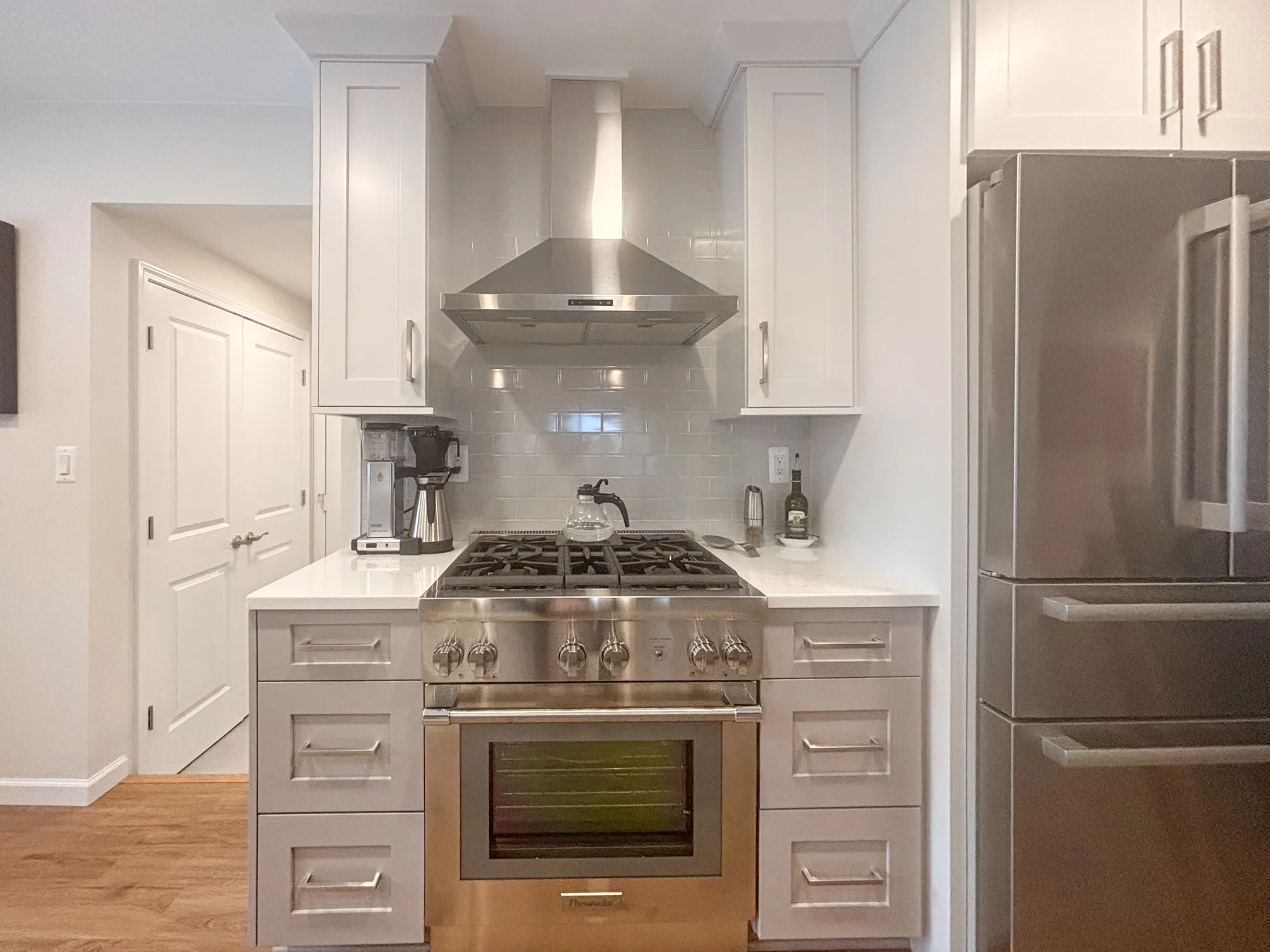 Contemporary kitchen featuring stainless steel appliances, white cabinets, and a gas range with a hood.