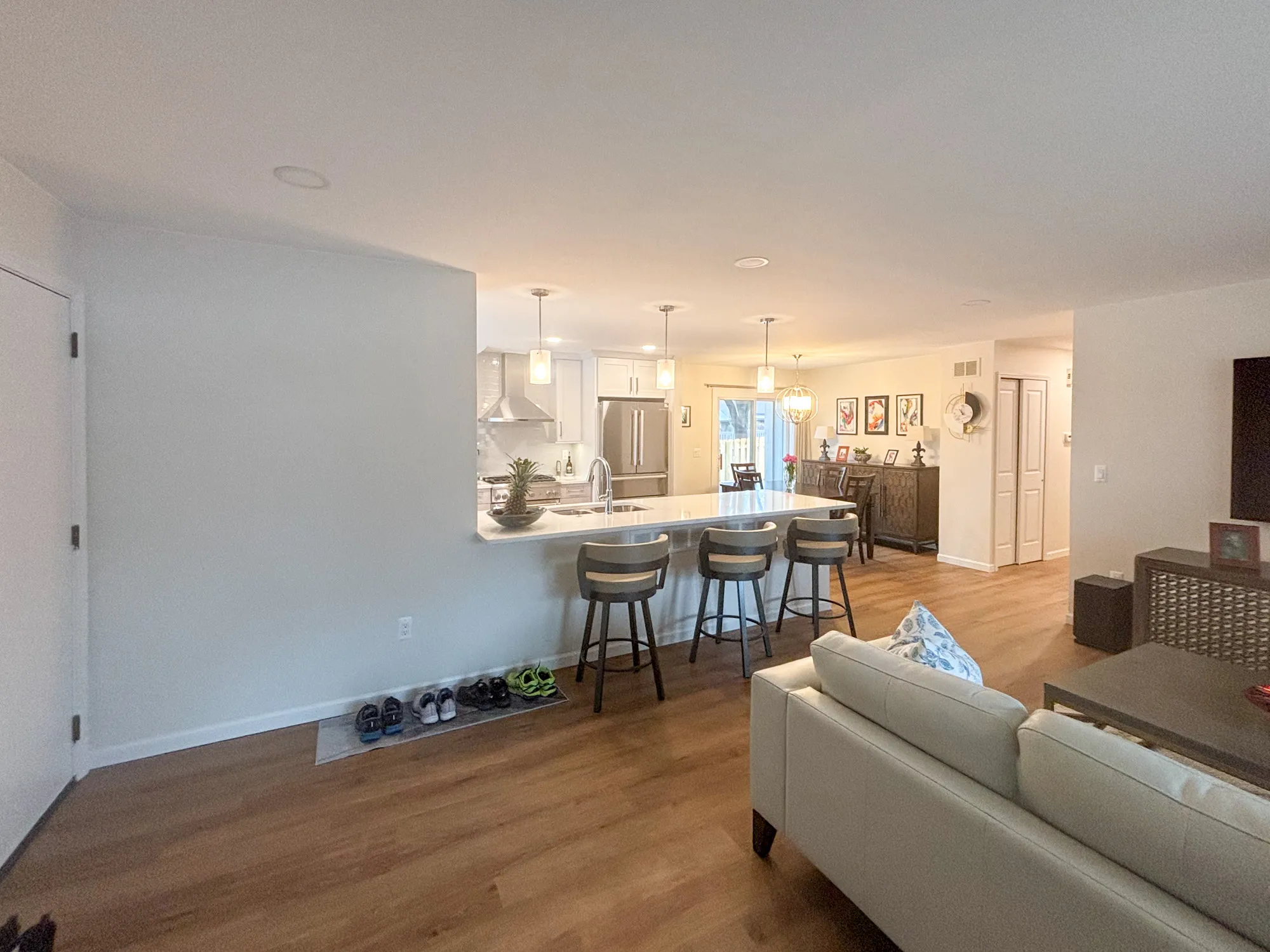 Spacious modern living room with an open kitchen featuring a large island and stylish pendant lights.