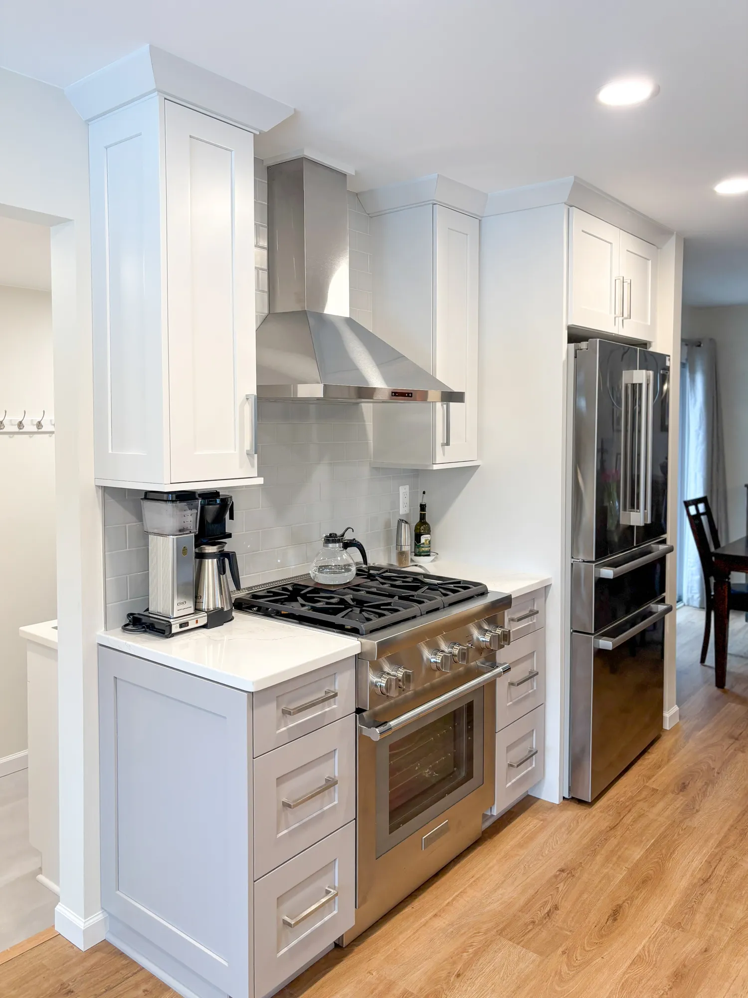Modern kitchen with gray cabinets and stainless steel appliances featuring a gas range and hood.