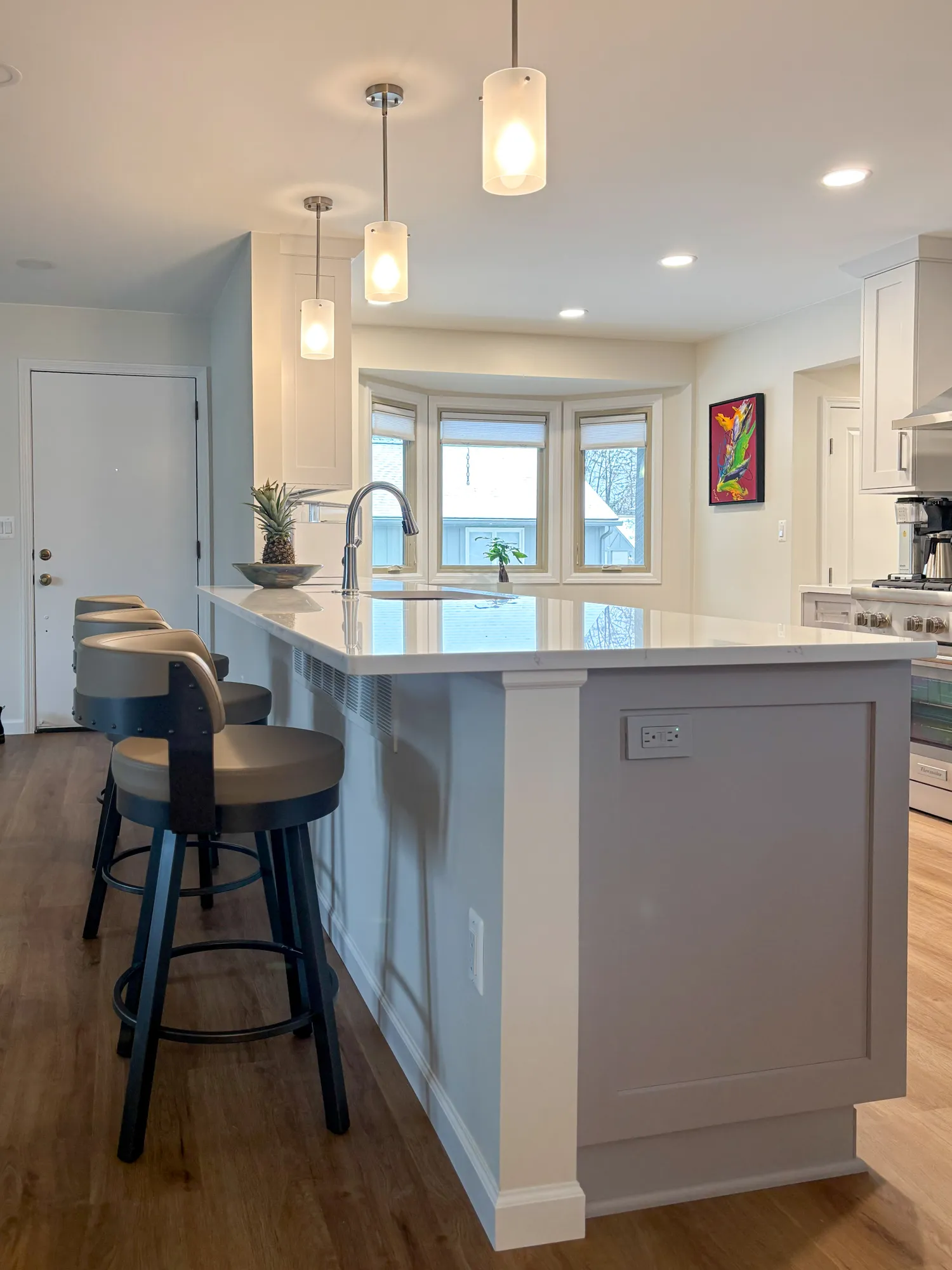 Modern kitchen featuring a sleek island with seating, pendant lights, and large windows, creating a bright and inviting space.