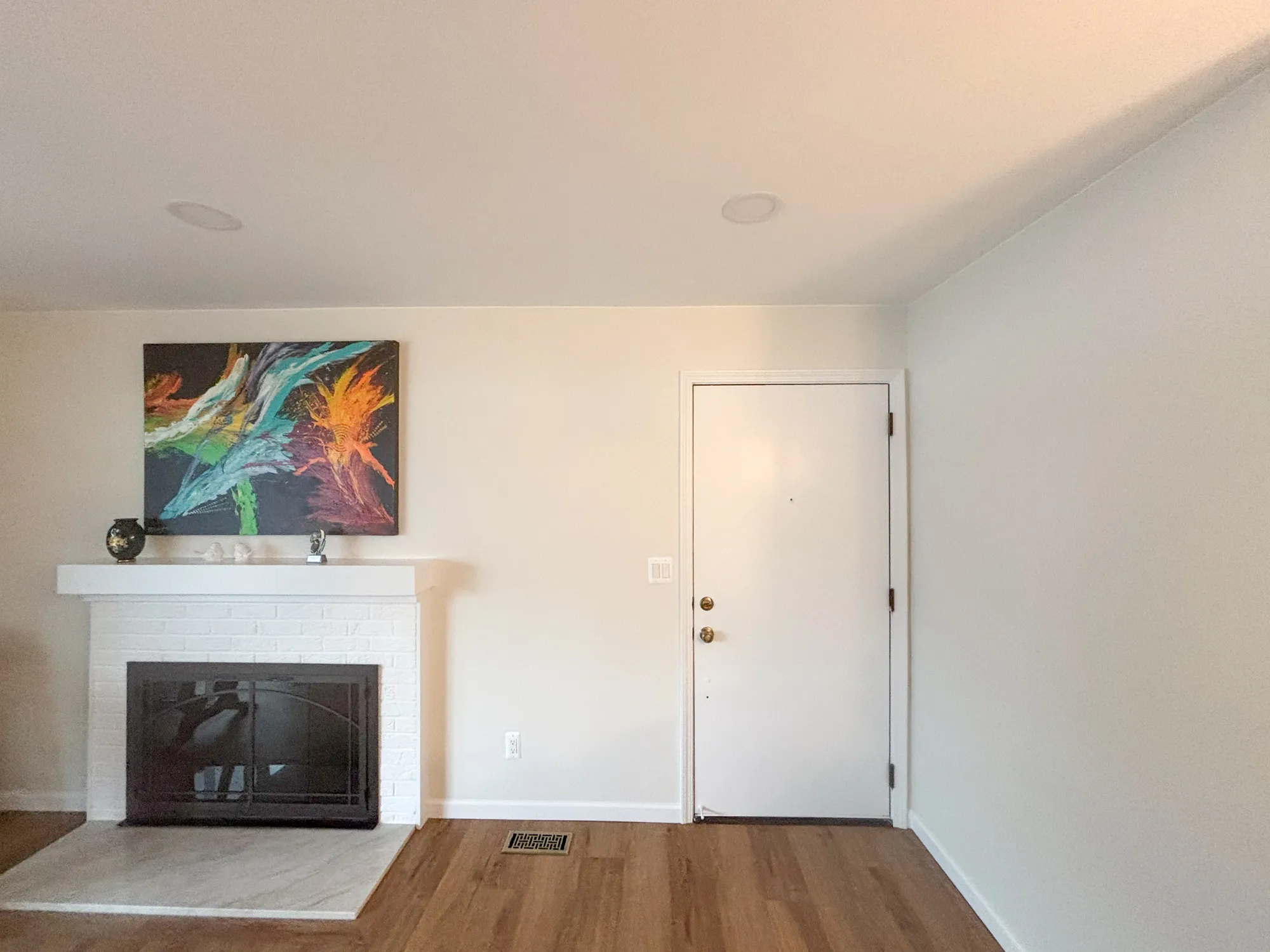 Contemporary living room featuring a colorful abstract painting and a white brick fireplace