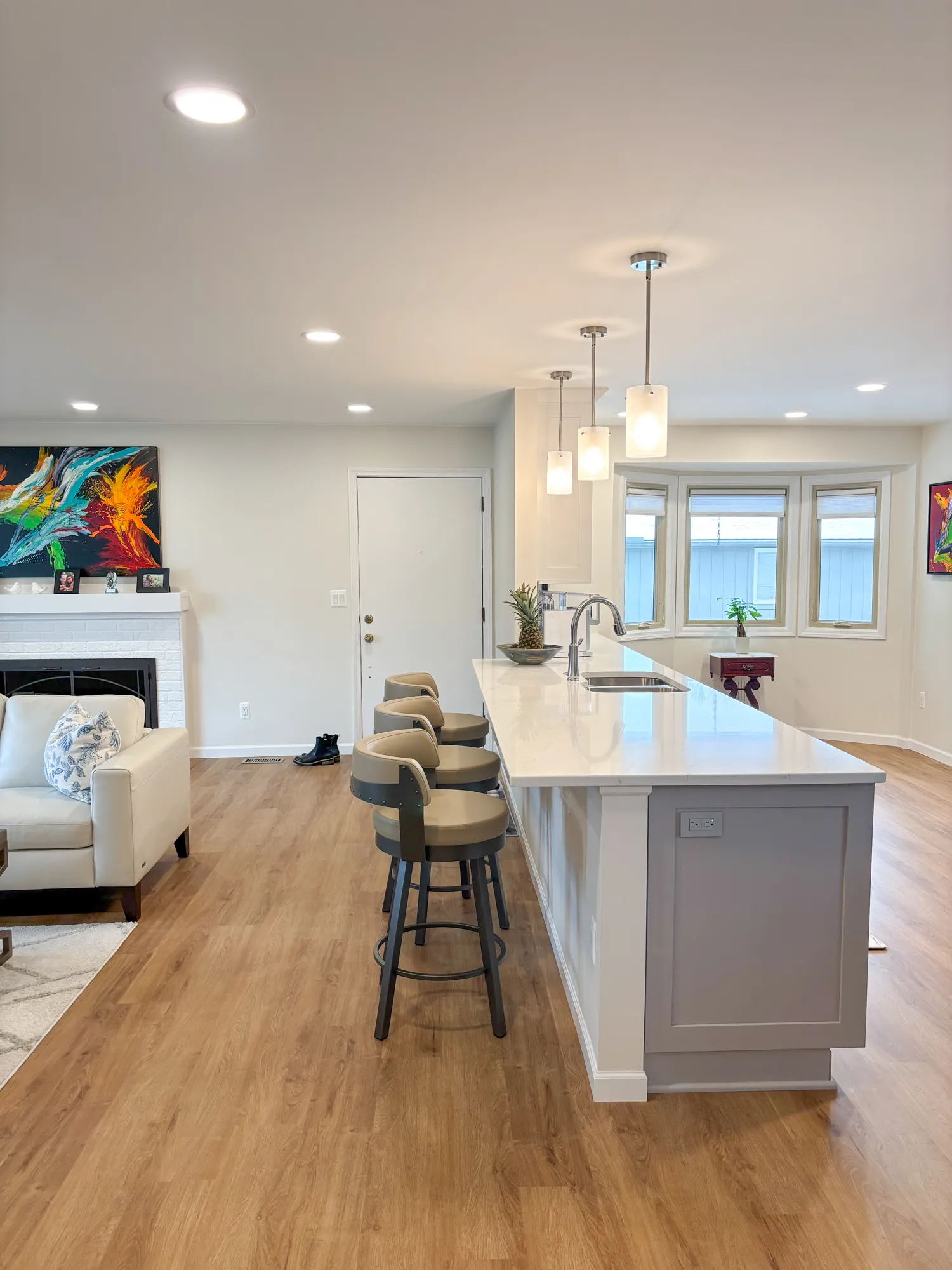 Modern kitchen with gray and white cabinetry, featuring a long island with seating and contemporary fixtures