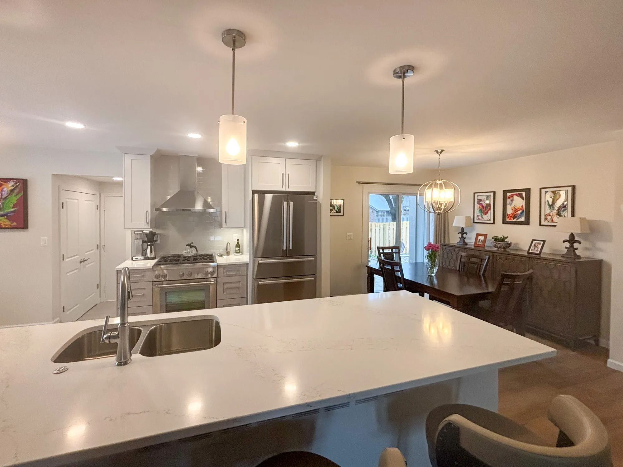 Modern kitchen and dining area with white cabinetry and stainless steel appliances