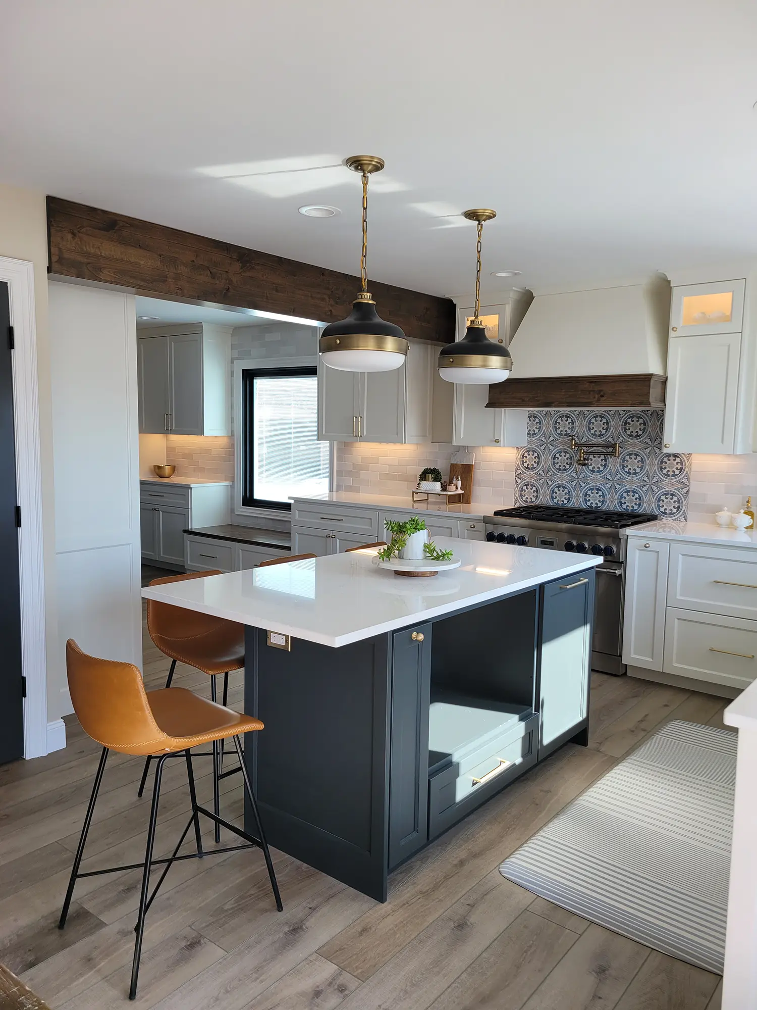 Modern kitchen with a navy island, white cabinets, and pendant lights