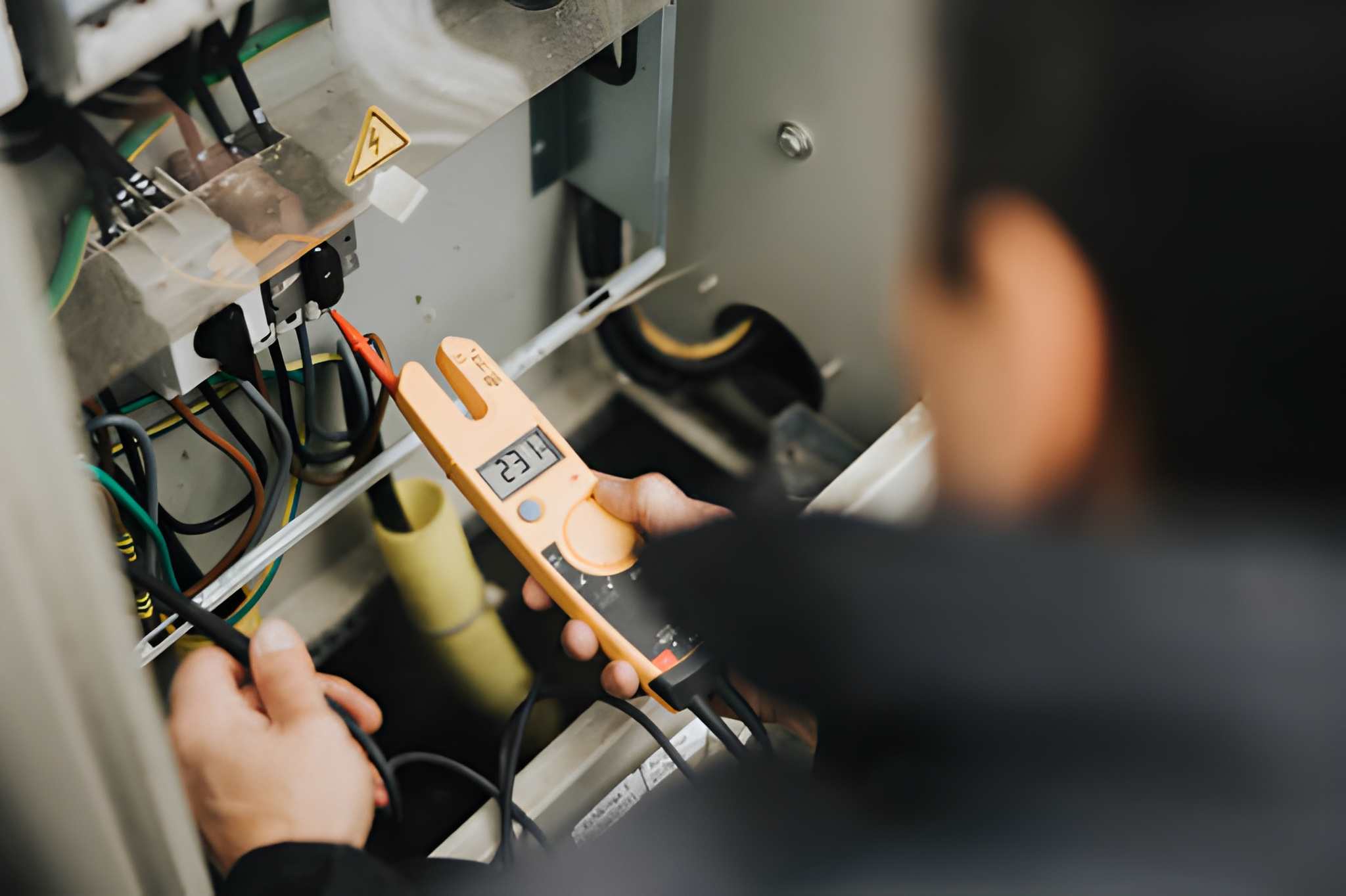 Electrician using multimeter to check voltage in electrical panel